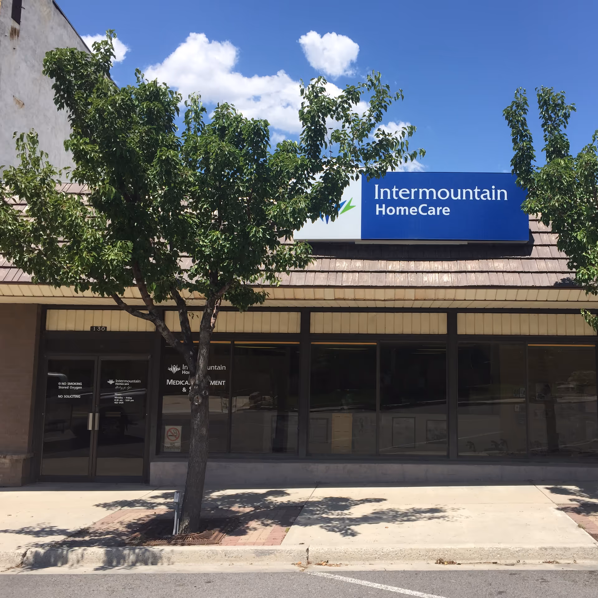 Exterior storefront with Intermountain HomeCare sign, large windows, and trees.
