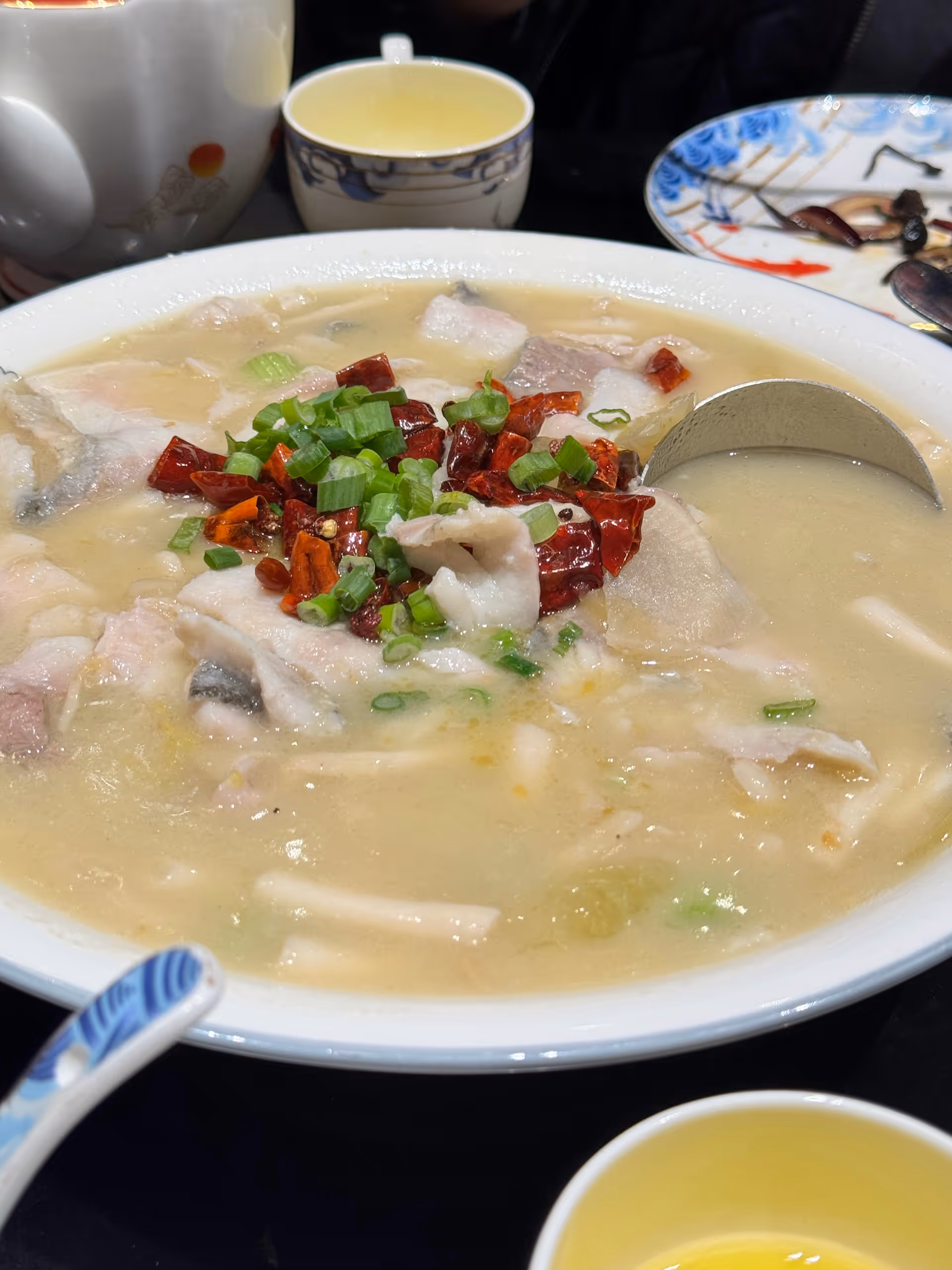 Close-up of a creamy soup bowl topped with chilies and green onions.