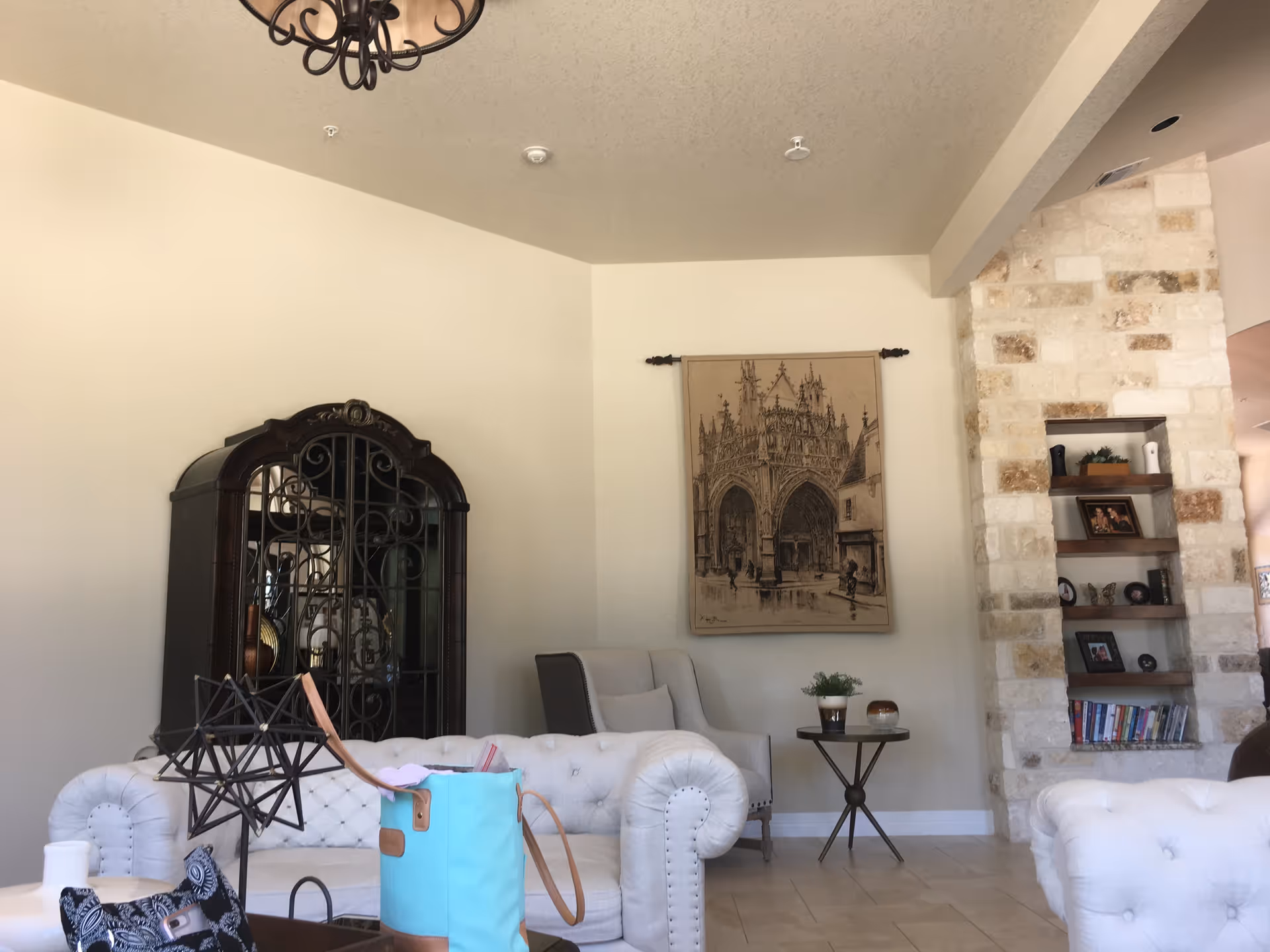 Bright living room with tufted sofas, a stone fireplace, and wall art.