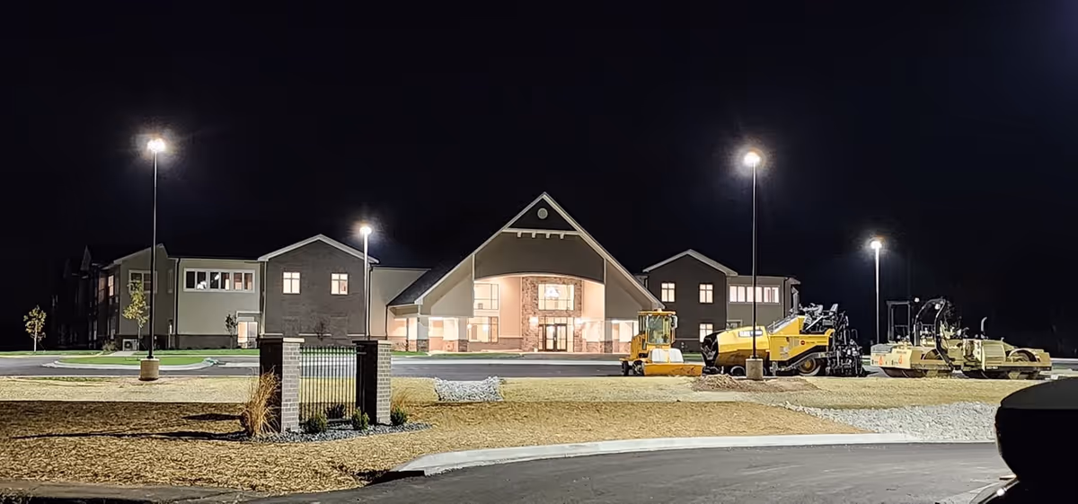 Night view of Autumn Trace Connersville Assisted Living exterior with lit entrance and construction equipment outside