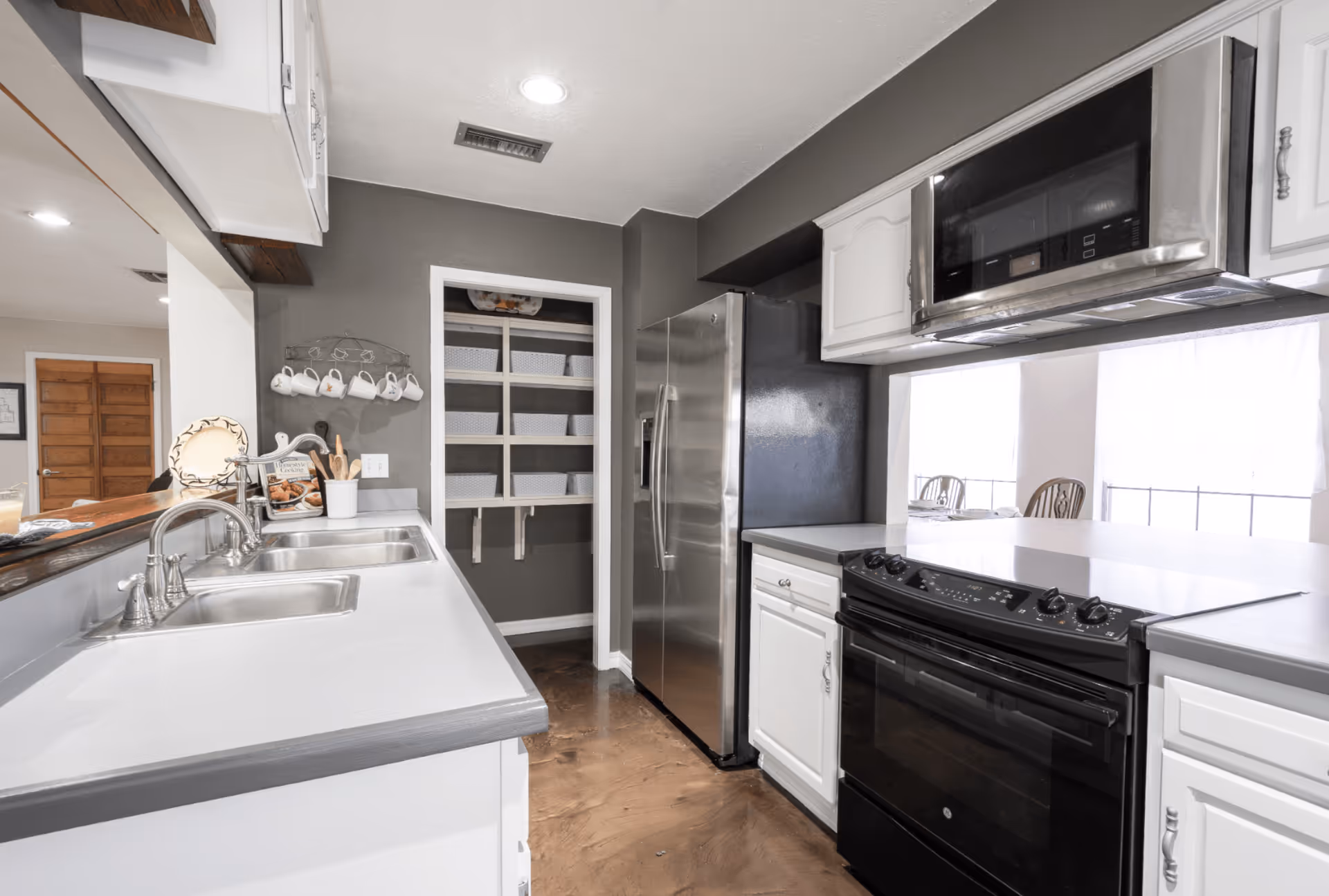 Modern kitchen with stainless steel appliances, white cabinetry, and a double sink.