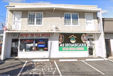 Two-story storefront building featuring A1 Homecare sign and neighboring tax service in a parking lot.