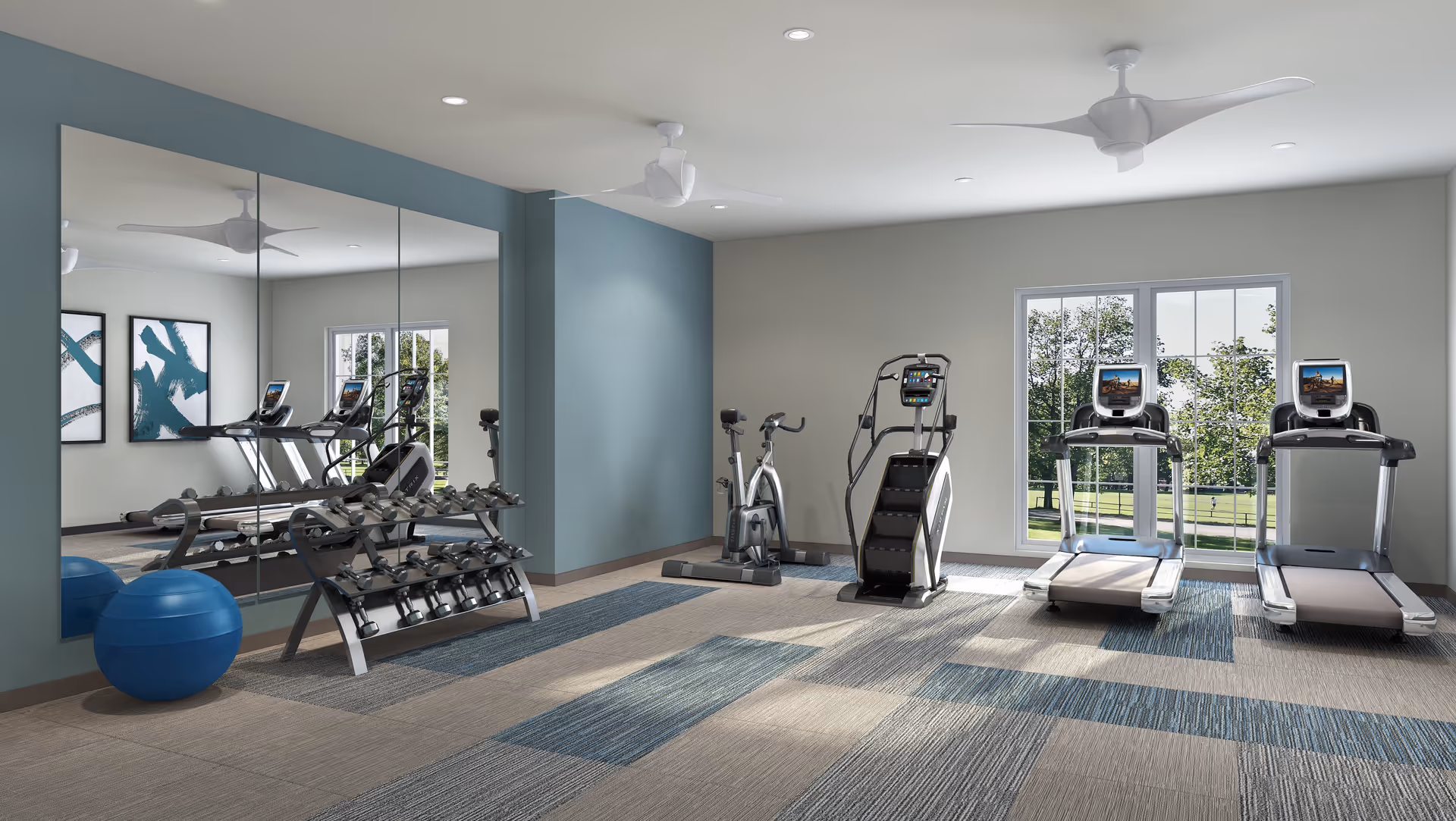 Bright fitness room with treadmills, an elliptical, a stationary bike, a rack of dumbbells, a mirror wall and an exercise ball.