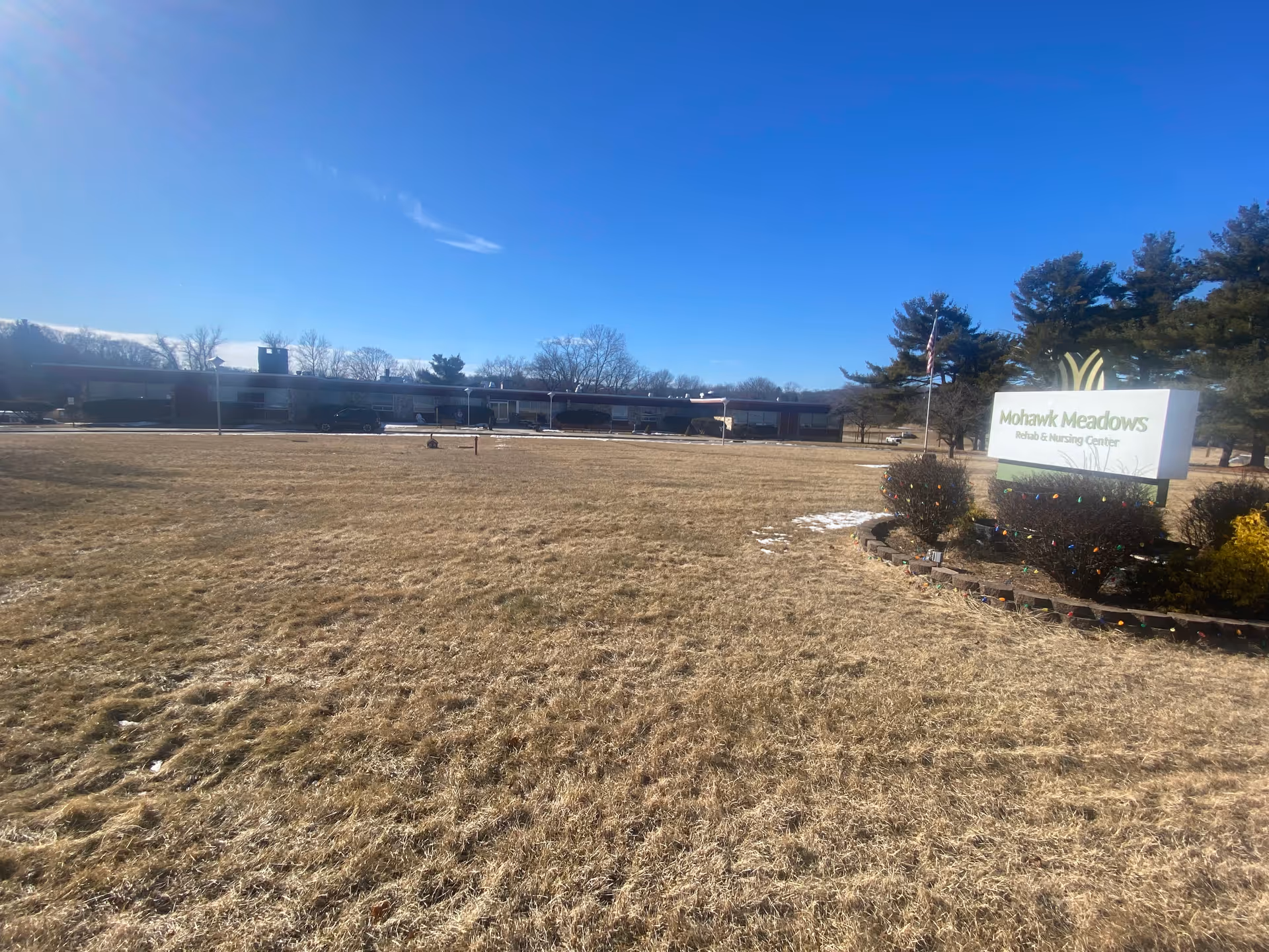Exterior view of Limecrest Subacute and Rehabilitation Center with sign and flag.
