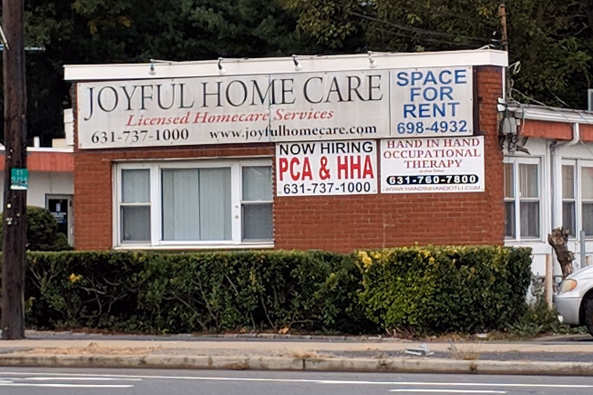A brick storefront with Joyful Home Care signage and banners along a sidewalk.