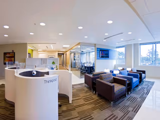 Bright lobby with reception desk, glass partitions, and blue seating in a senior living facility.
