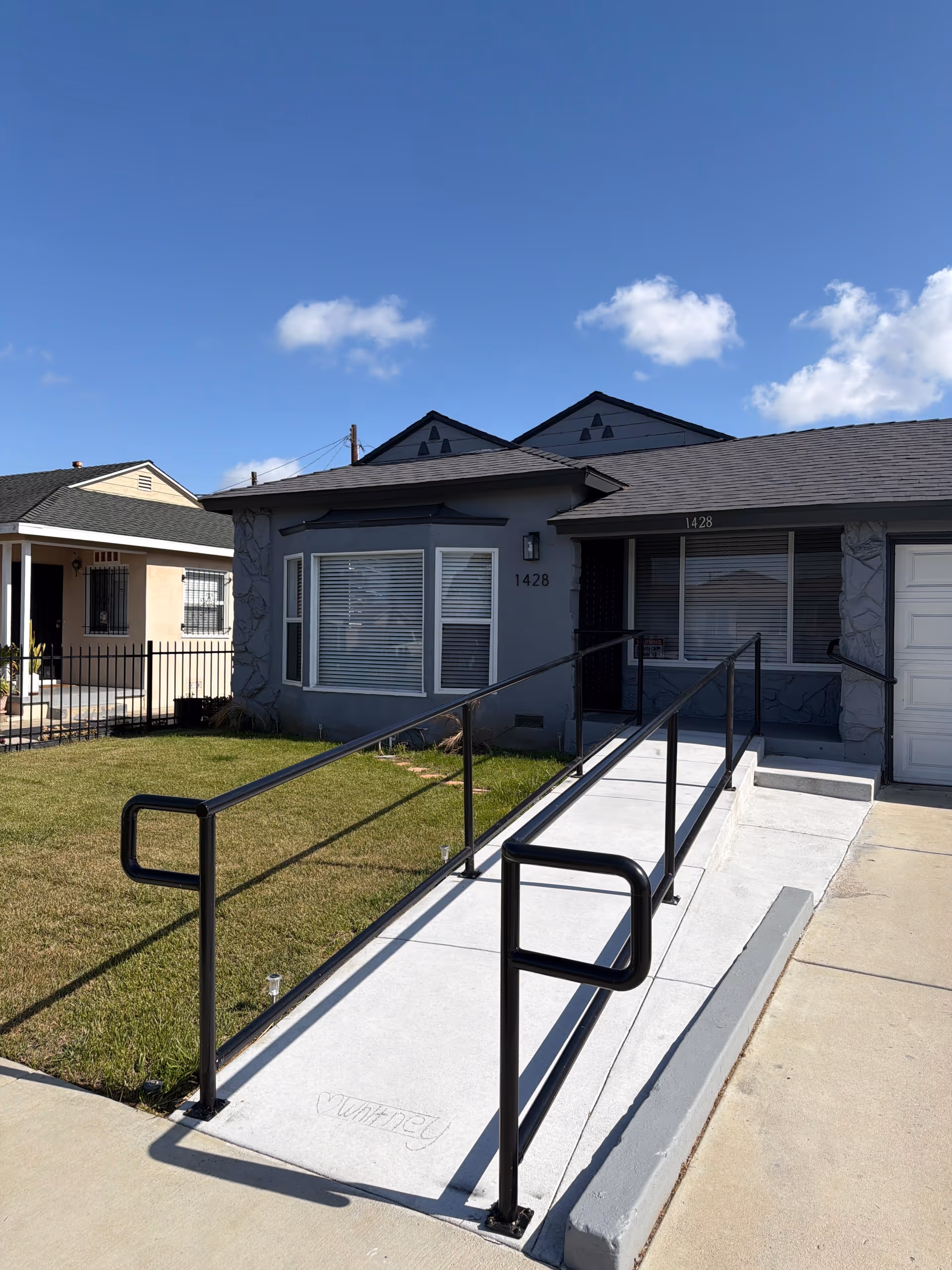 Exterior view of a single-story senior living facility with a ramp to the front entrance.