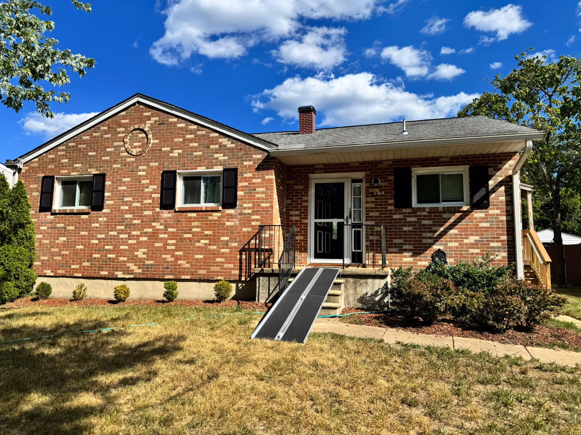 Brick, single-story assisted living building with ramped entrance and front yard.