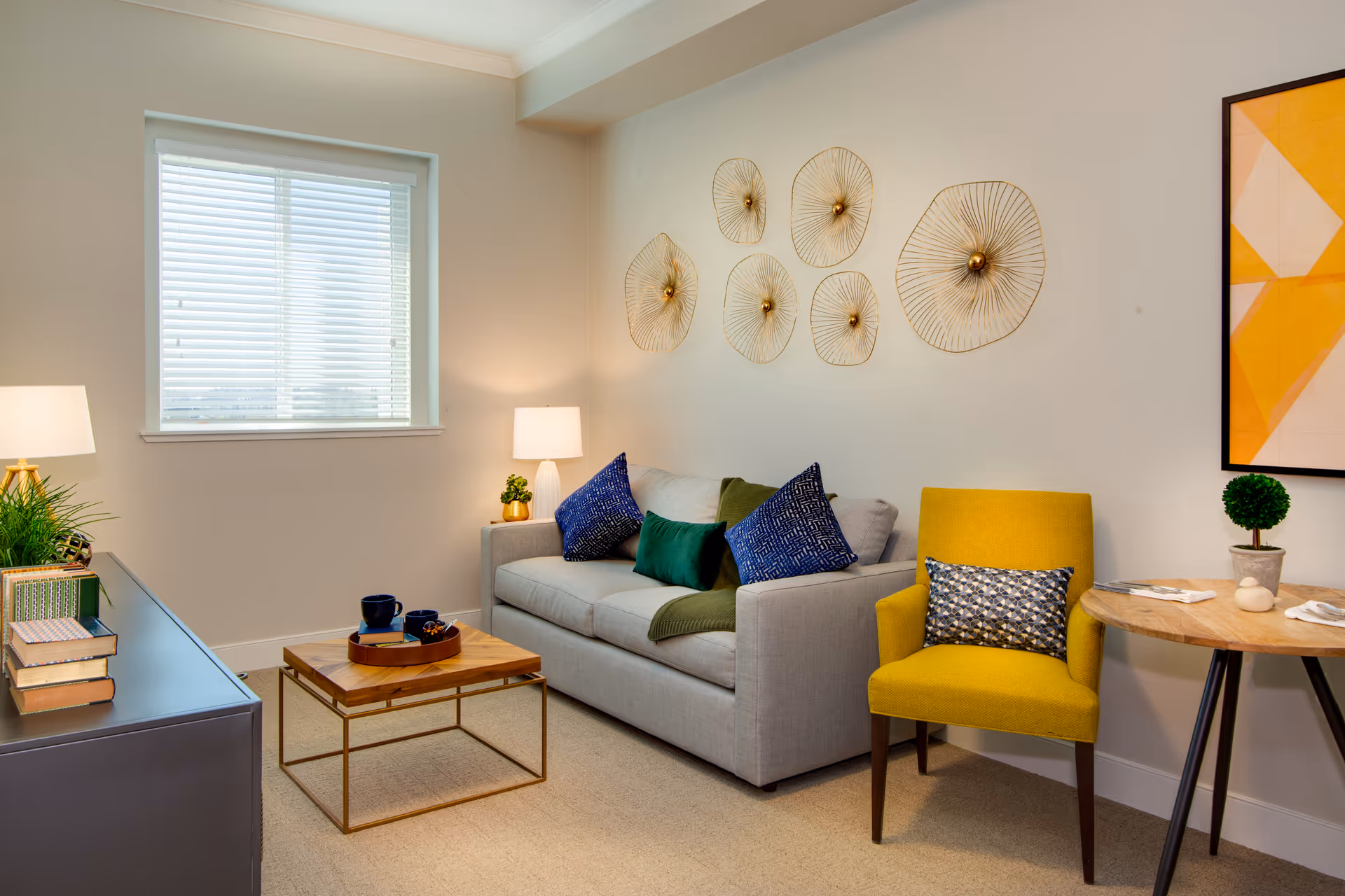 A bright living room in Sage Glendale with sofa, yellow chair, coffee table, and wall decor.