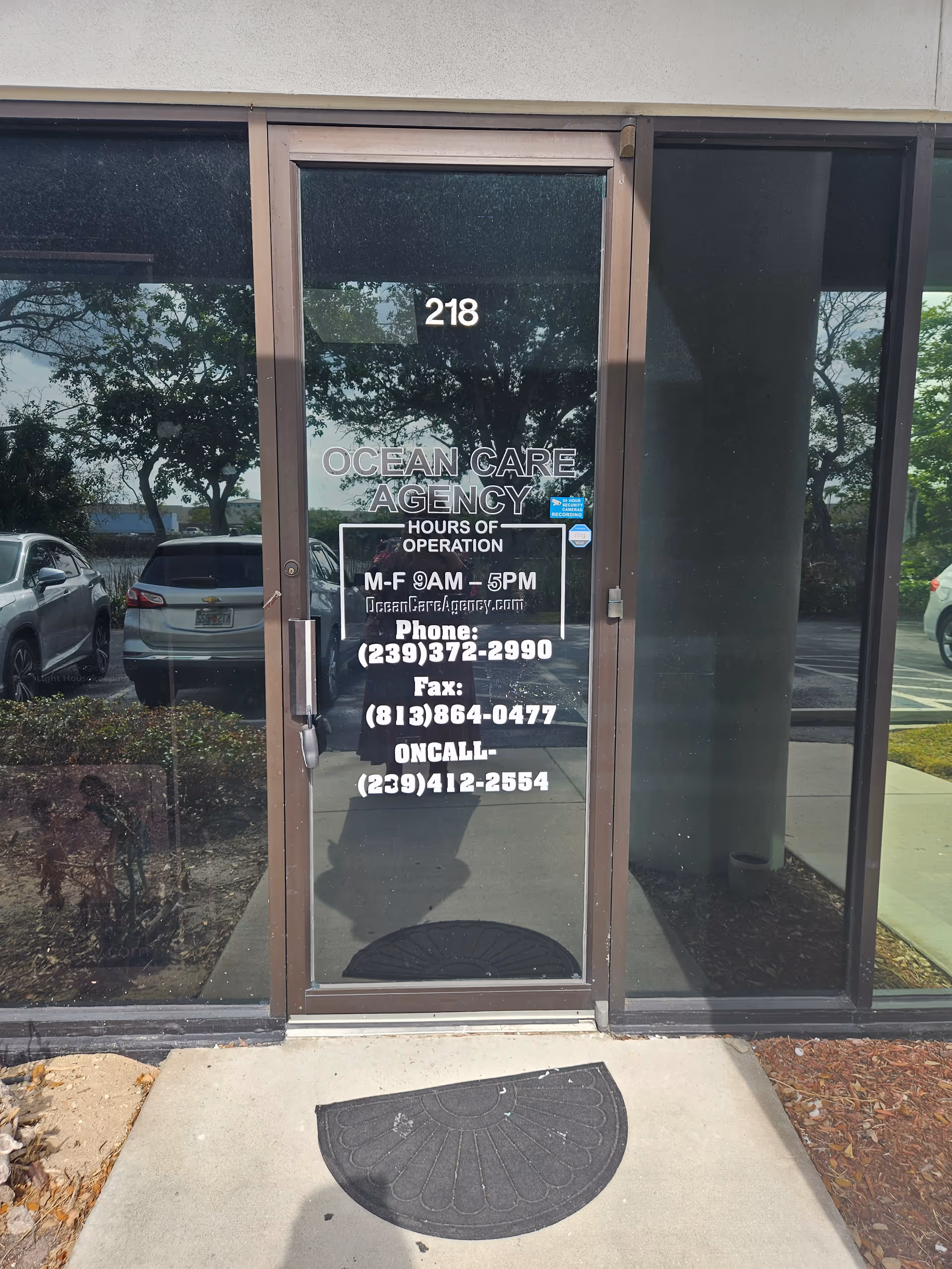 Exterior glass door of Ocean Care Agency with hours and contact details.