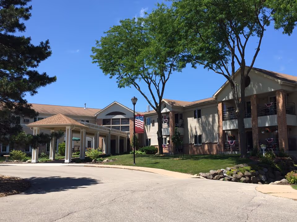 Exterior view of Trinity Pines Retirement Center with entrance, flag, trees, and a driveway.