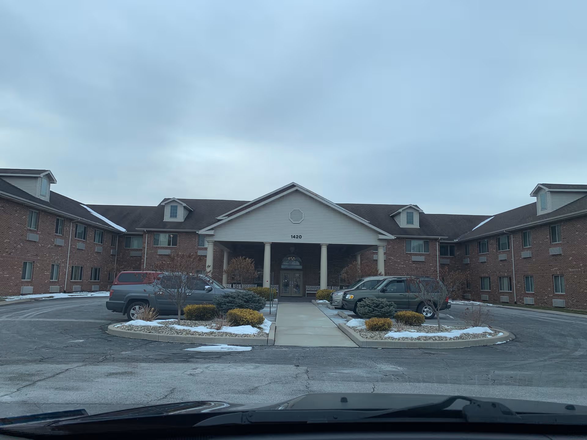 Front exterior of Brentwood at Hobart Senior Living with parked cars