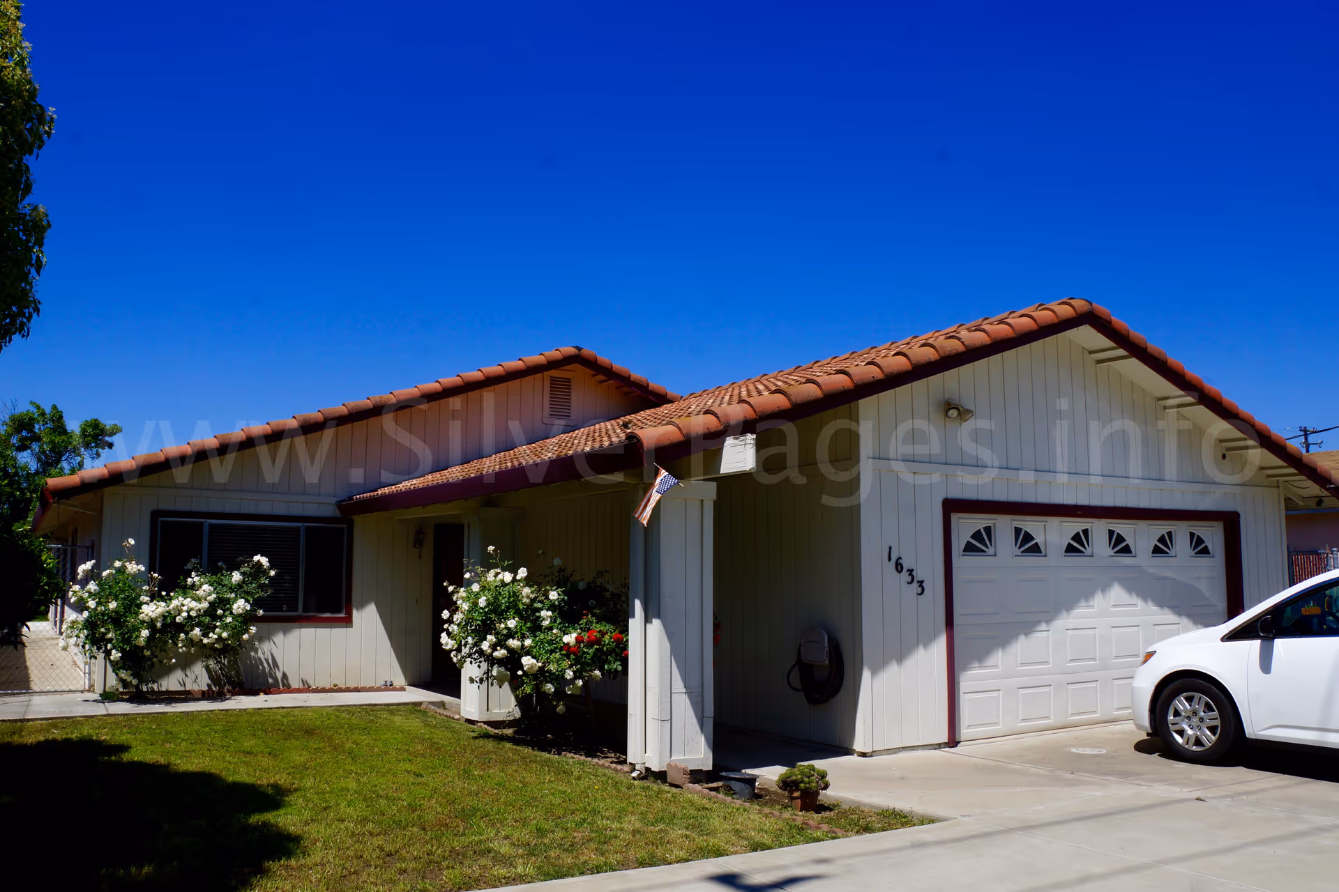 Front exterior of Arlyn's Guest Home, a single-story building with a garage and white car.