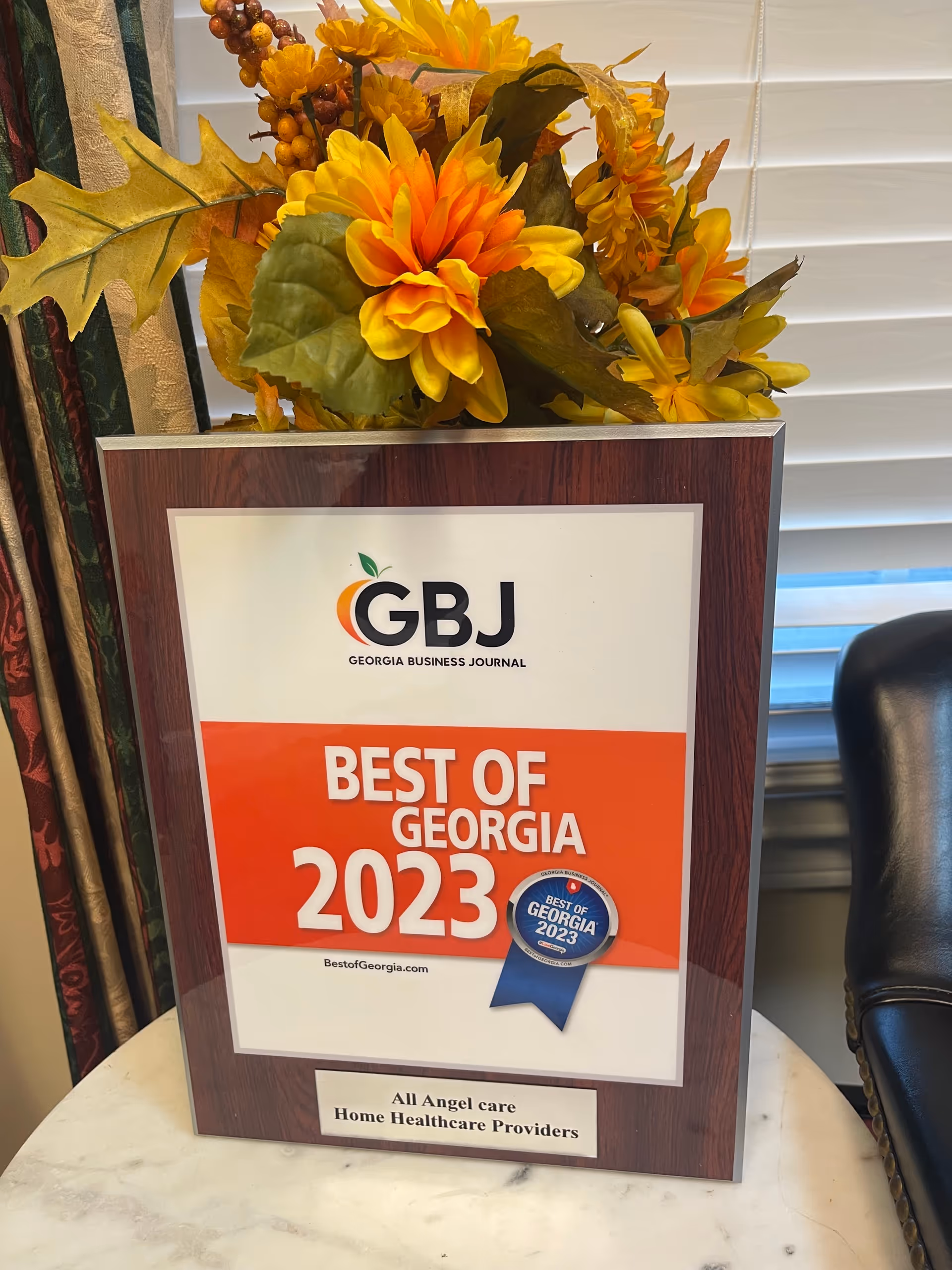 Framed Best of Georgia 2023 award with autumn flowers on marble table.