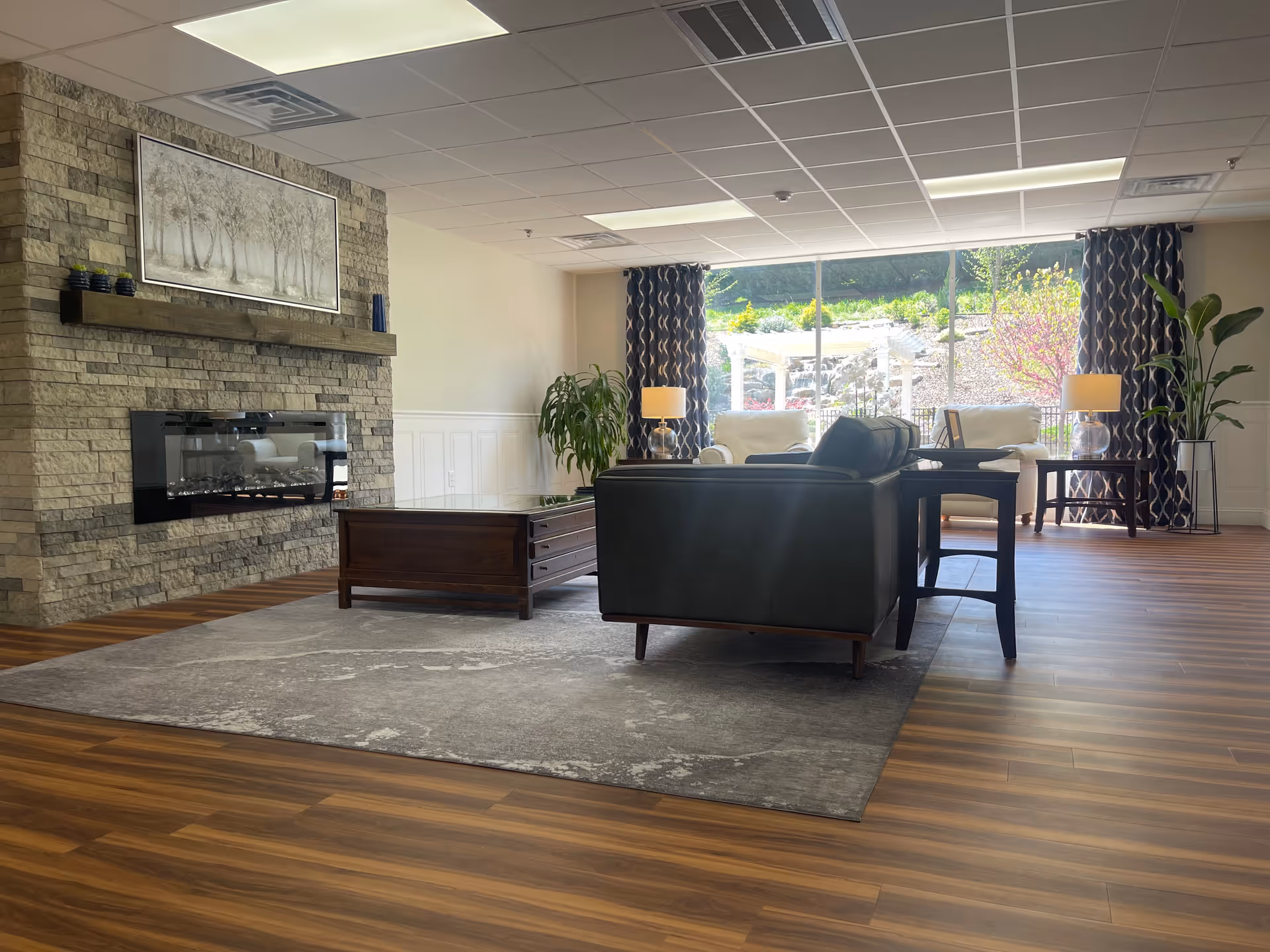 Spacious lounge with leather sofa, fireplace, and large windows overlooking outdoor seating.