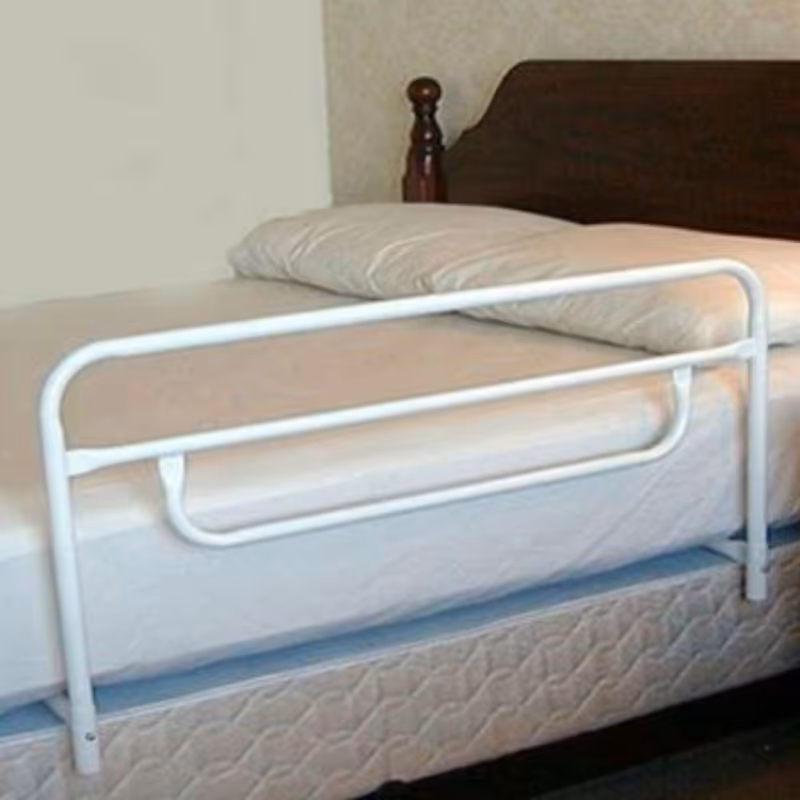 A white metal hospital-style bed in a small bedroom with a wooden headboard.