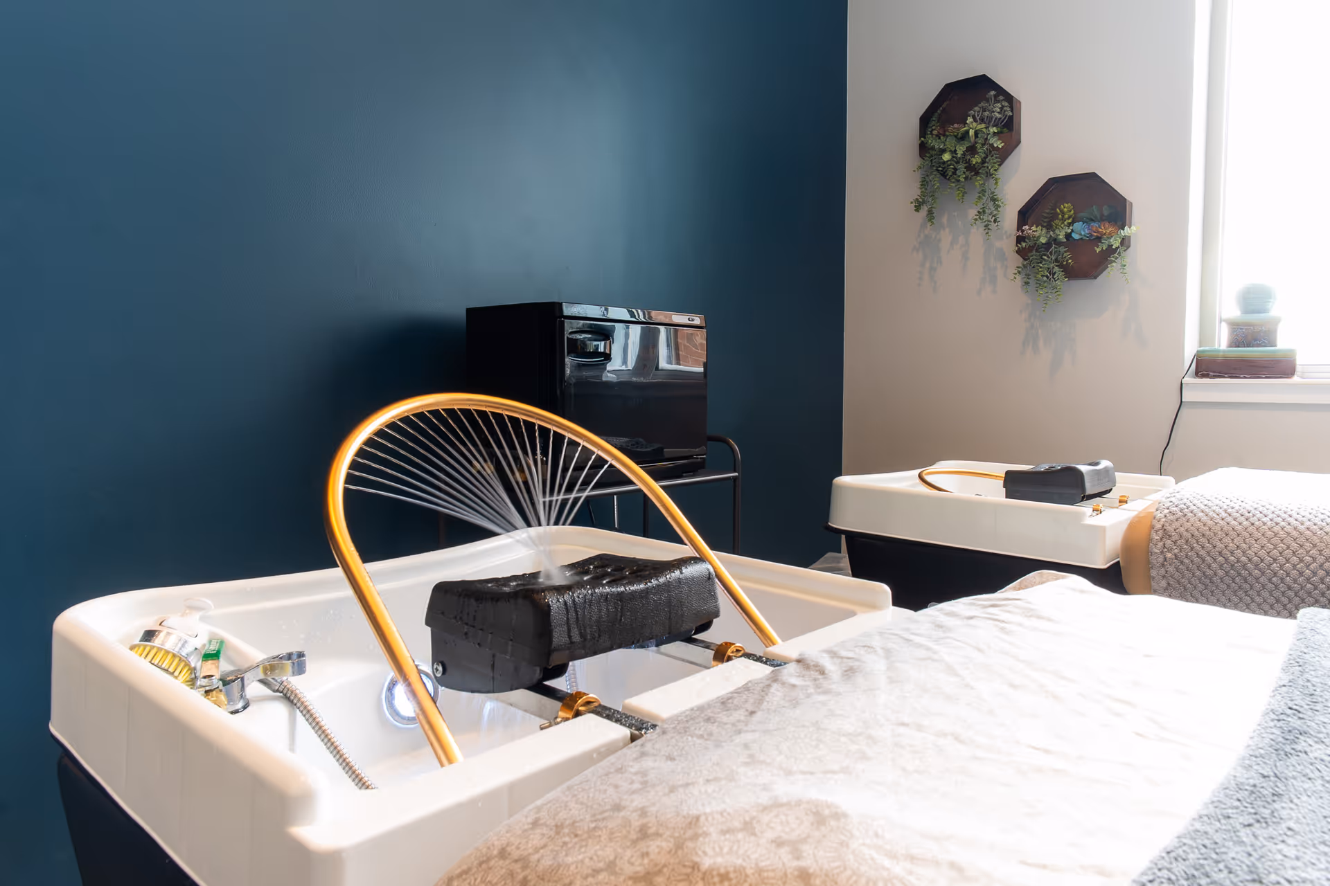 Hydrotherapy tub with hose and black headrest against blue wall.