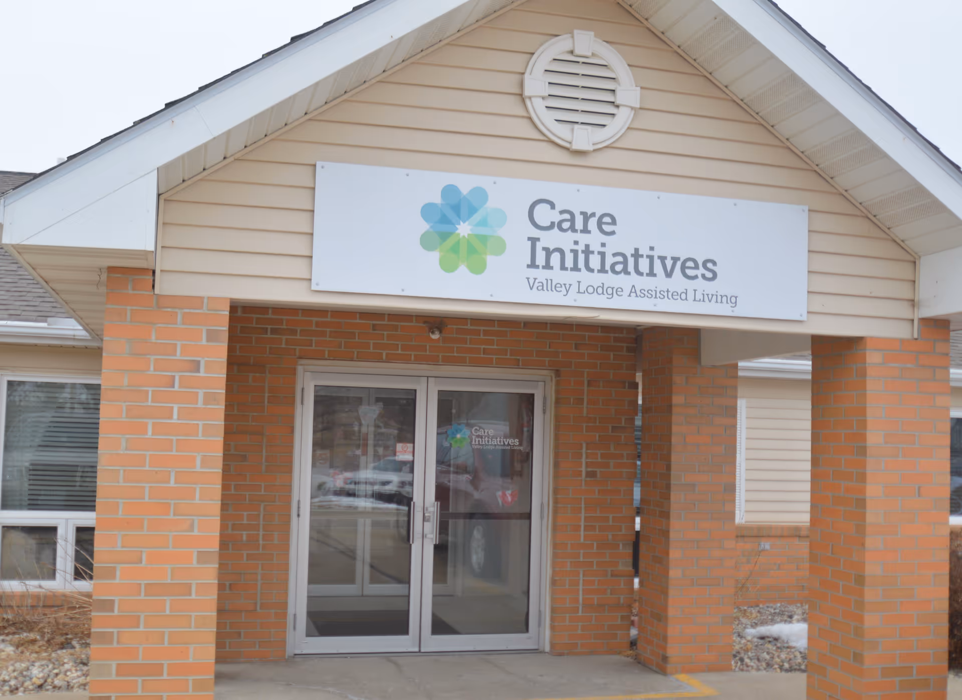 Front of a brick building with a Care Initiatives sign and glass doors.