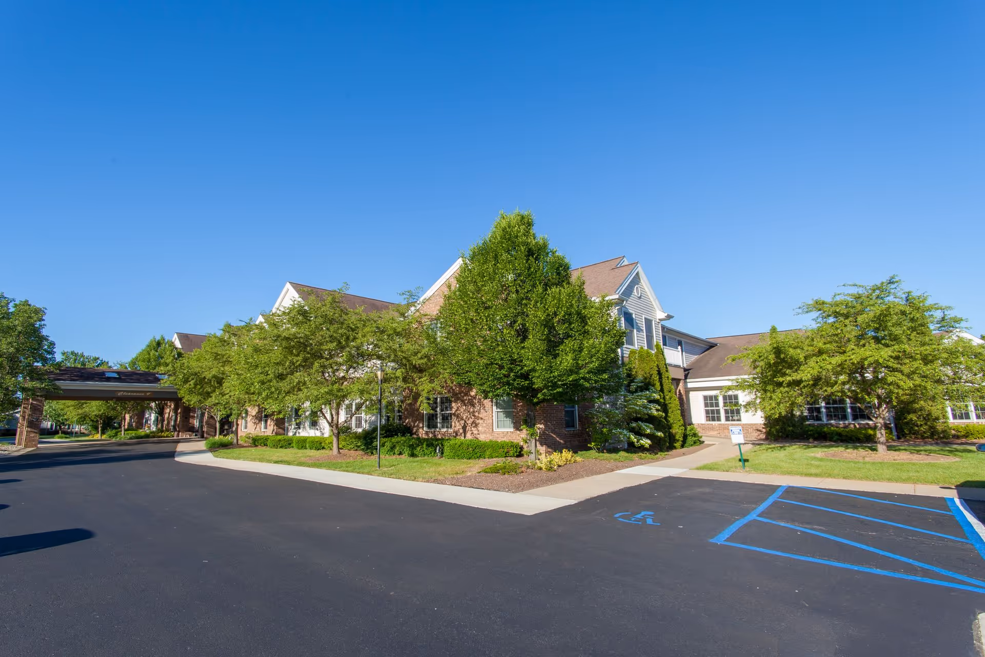 Sunny exterior view of Ganton's Countryside Retirement Community with trees and parking