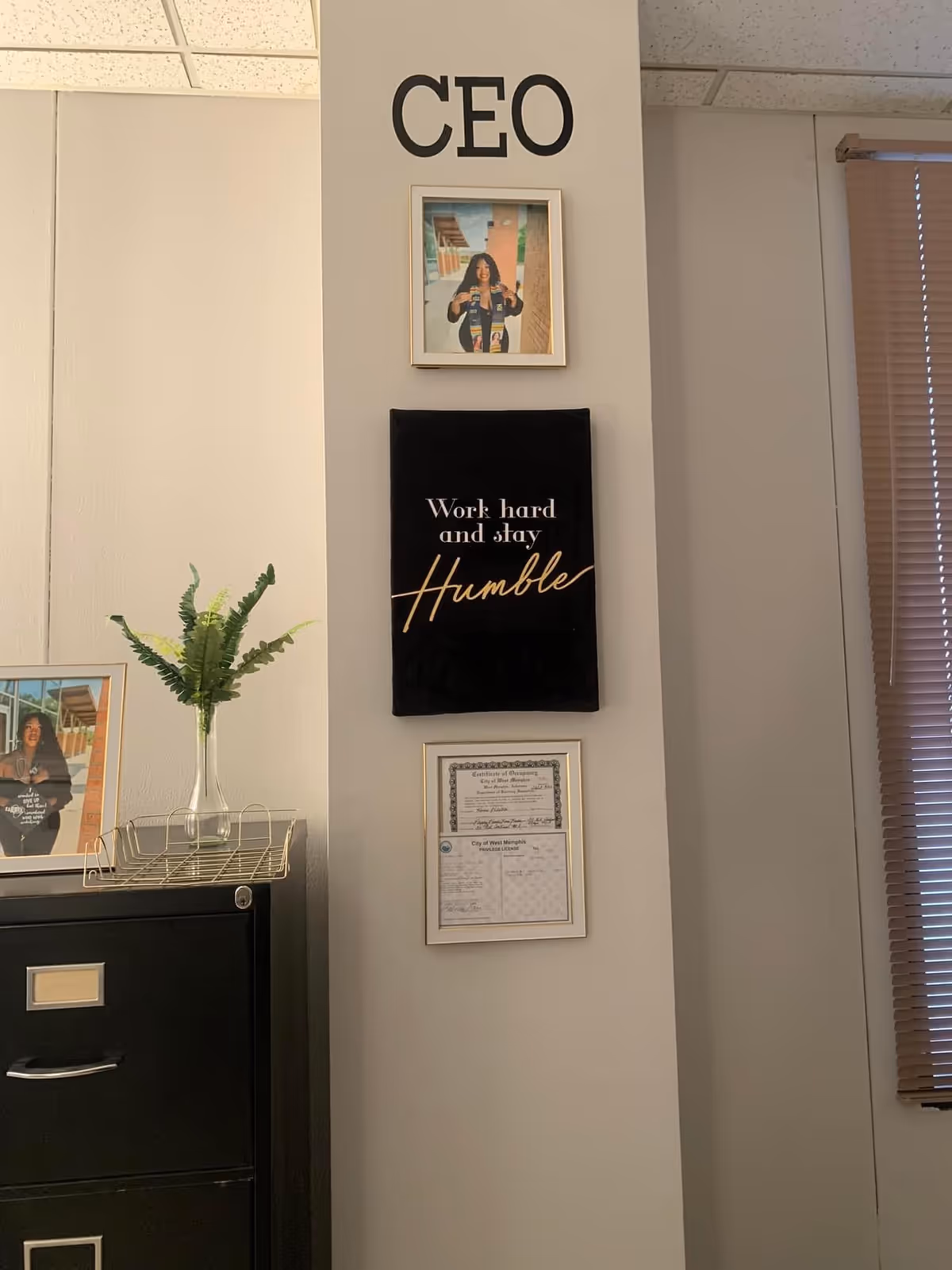 Office wall with CEO sign, framed photo, plaque, and certificate near a filing cabinet.