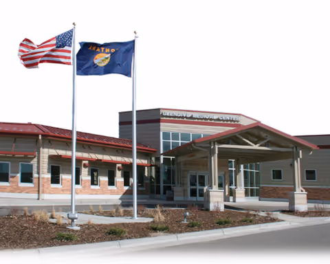 Exterior view of Glendive Medical Center entrance with flags and a glass facade.