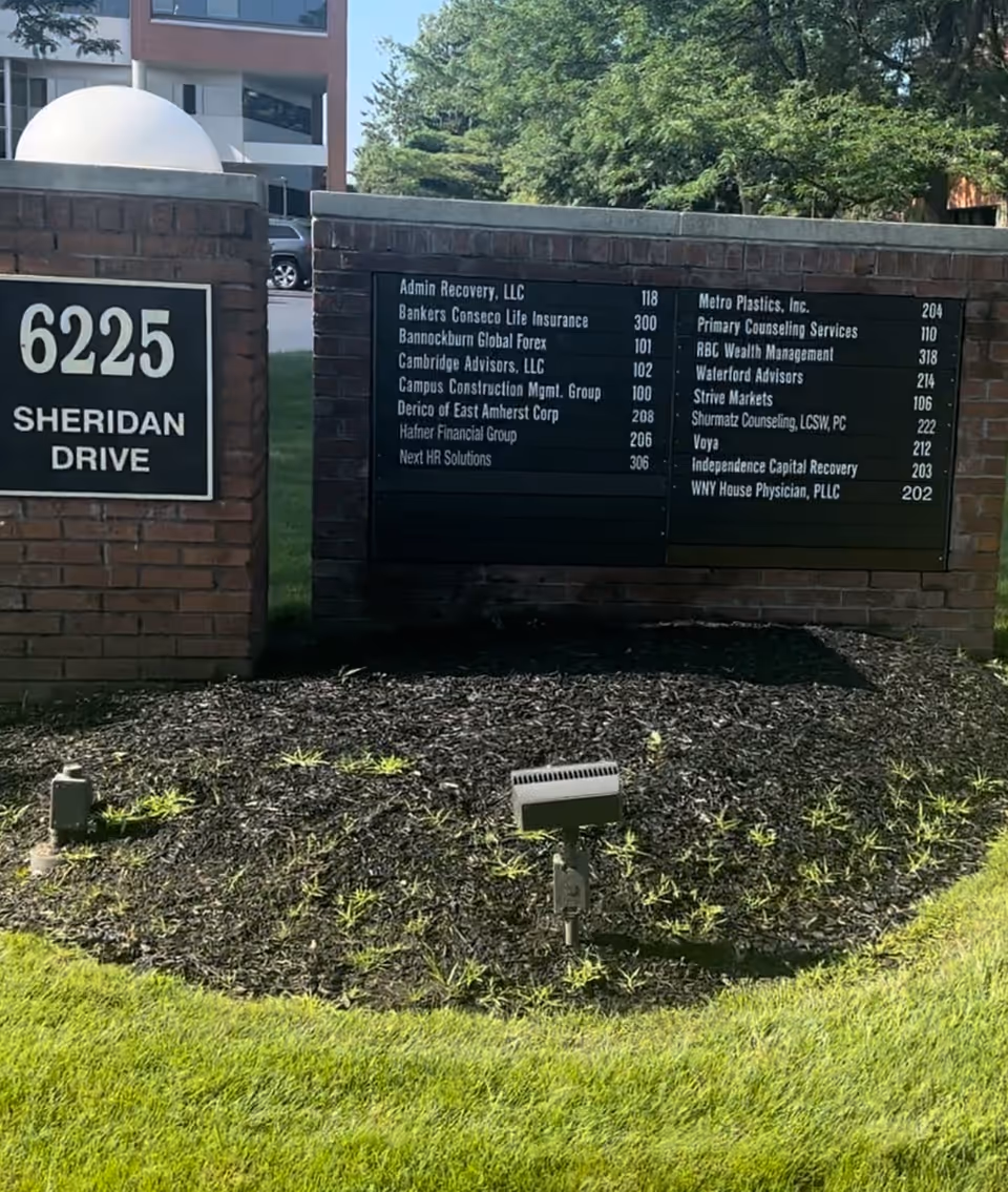 Exterior brick sign wall with directory board listing tenants on Sheridan Drive