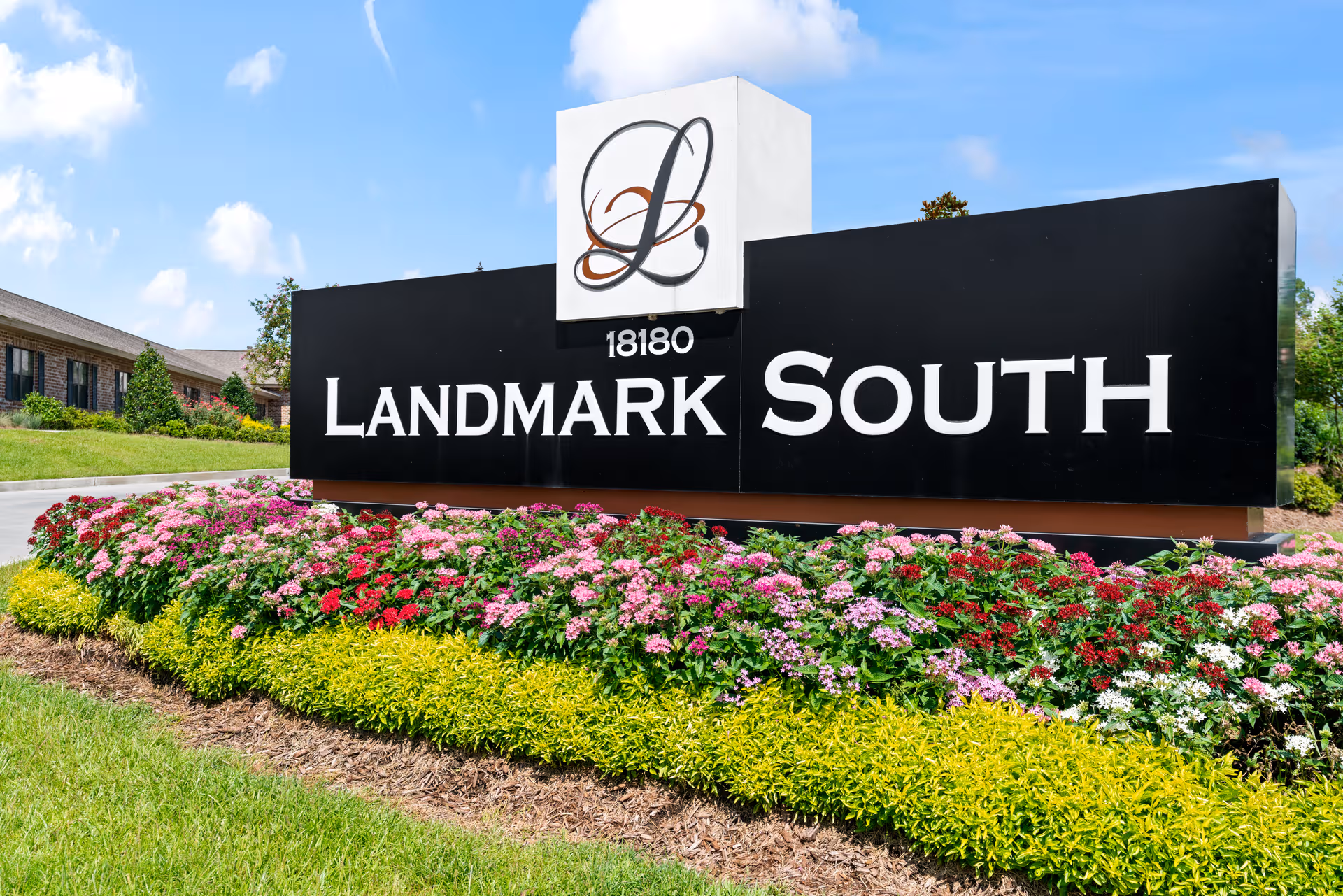 A large black Landmark South sign sits in front of a landscaped facility entrance.