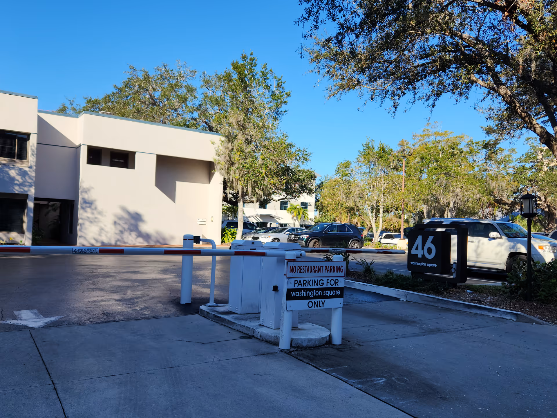 Modern two-story senior living facility exterior with a security barrier and parking lot.