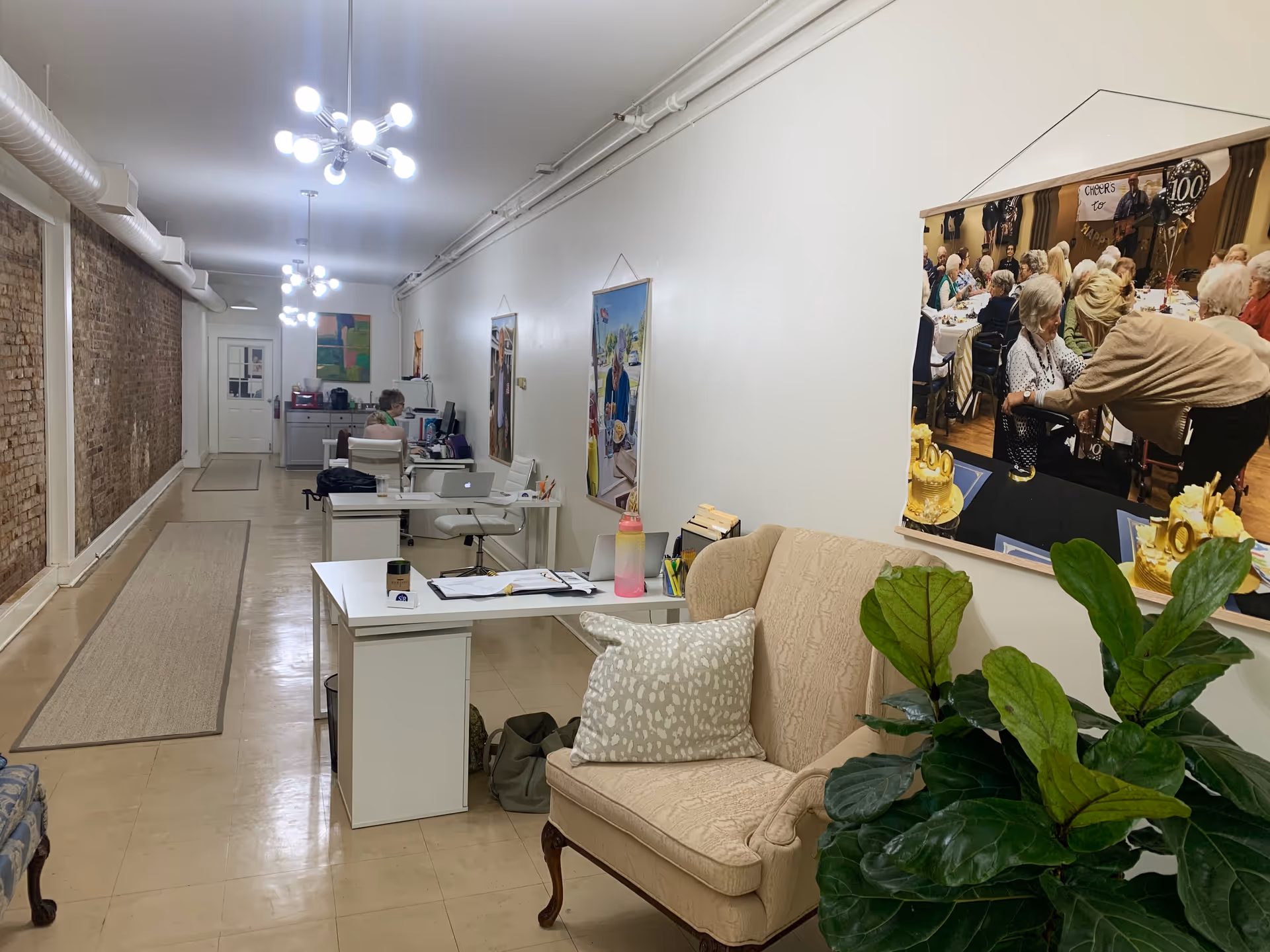 Reception area inside a senior care facility with desks, chairs, and wall art.