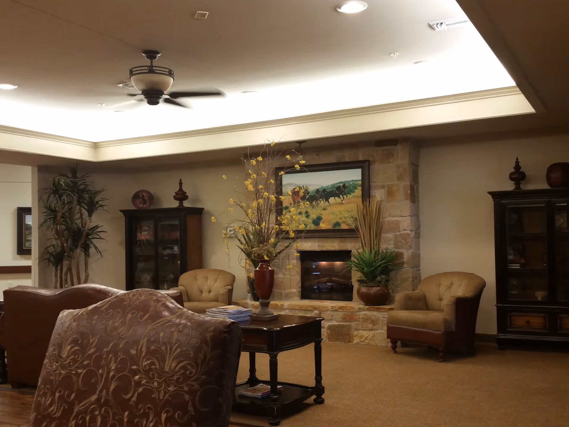 Cozy senior living lounge with fireplace, plants, and comfortable seating.