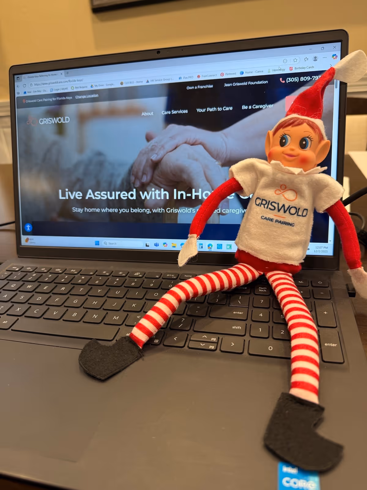 A laptop on a desk displays the Griswold Florida Keys site, with a plush elf toy.