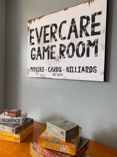 Sign reading EverCare Game Room on wall above a table with board games