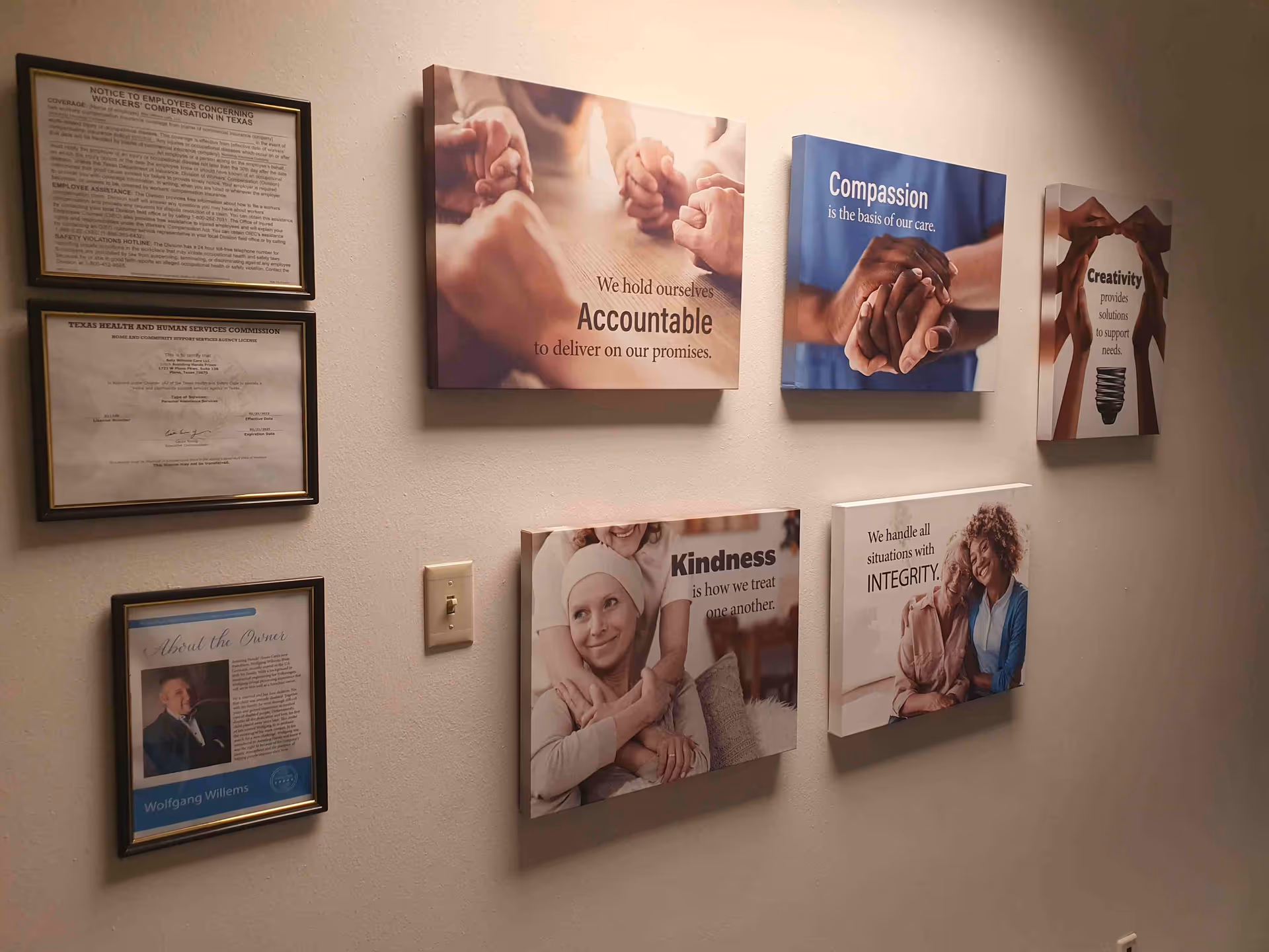 Interior hallway of a senior living facility with framed posters and certificates on the wall.