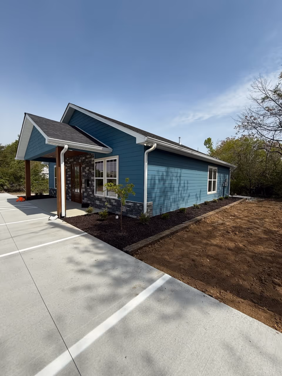 Blue, single-story senior care facility exterior with stone accents and parking.