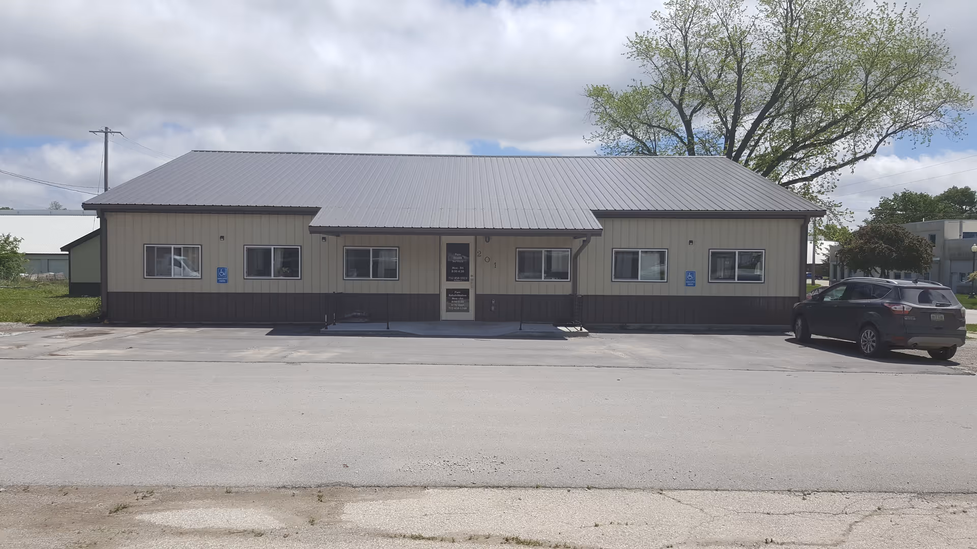 Exterior of a single-story rehabilitation facility with a metal roof and a parked car.