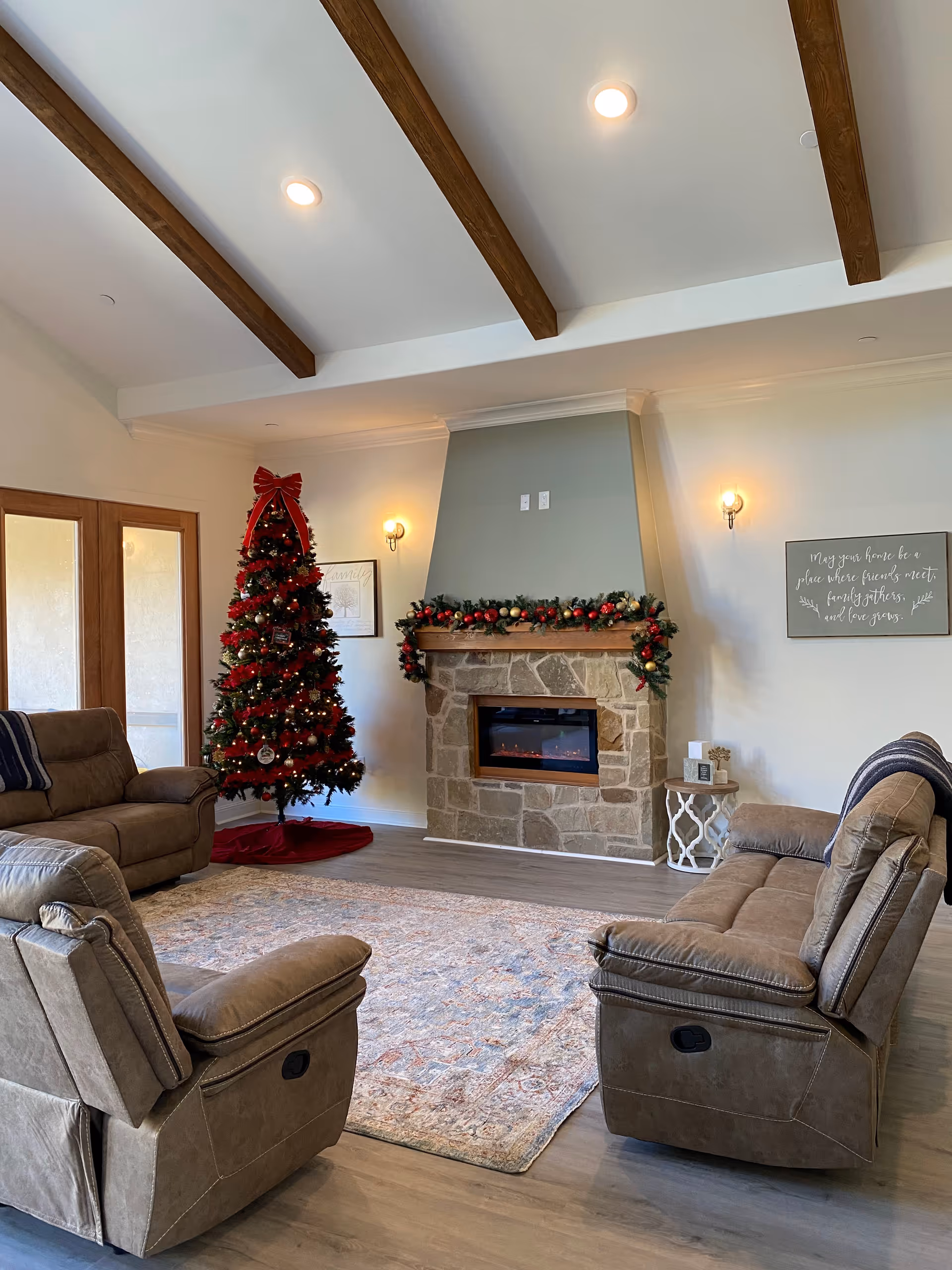 Cozy living room with Christmas tree, stone fireplace, and plush recliner seating.