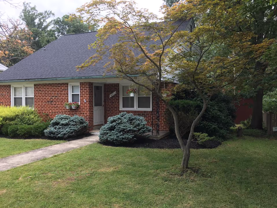 Brick single-story facility entrance with green lawn, shrubs, and a tree in front yard.