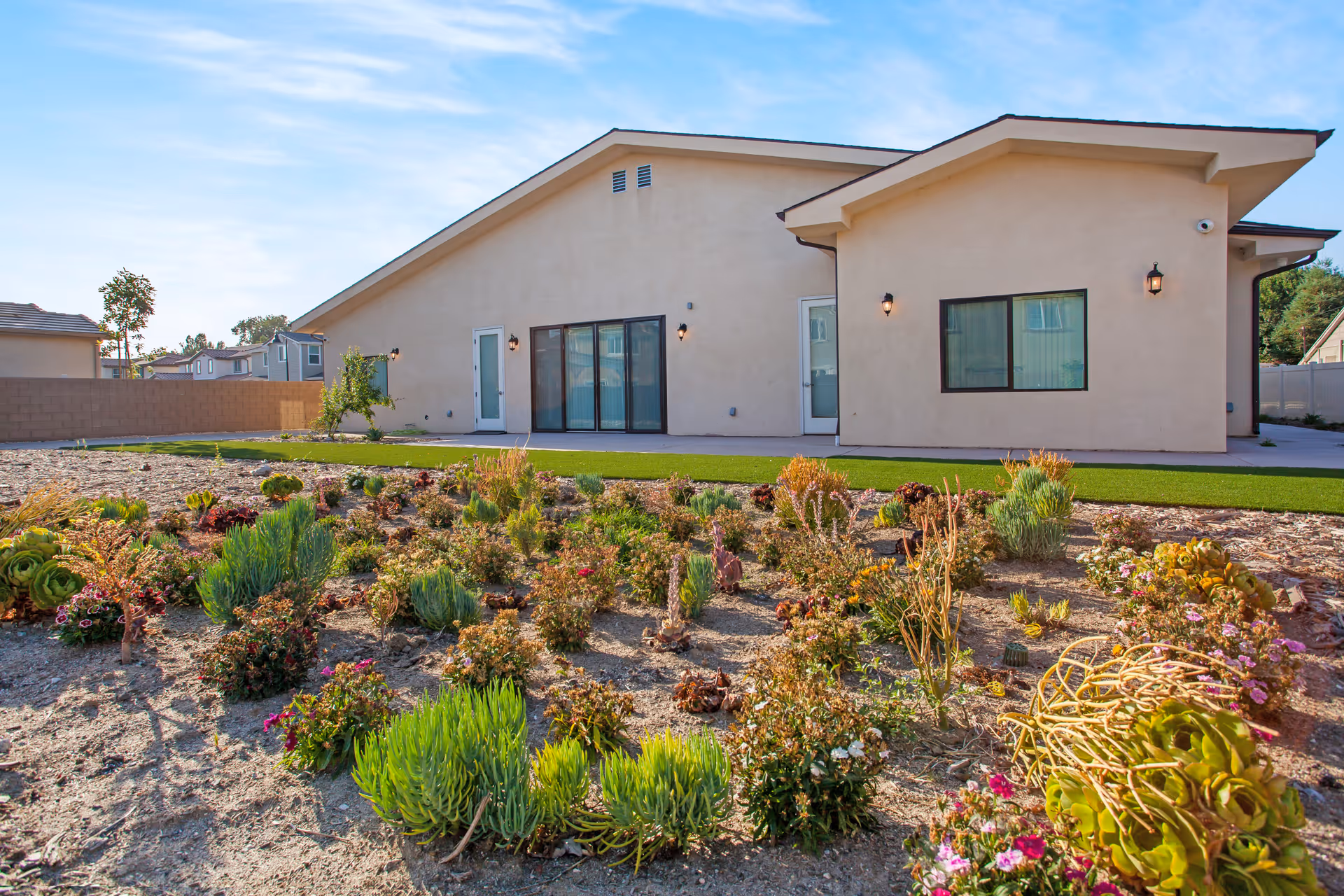 Single-story beige senior living facility with desert garden landscaping in front and clear sky