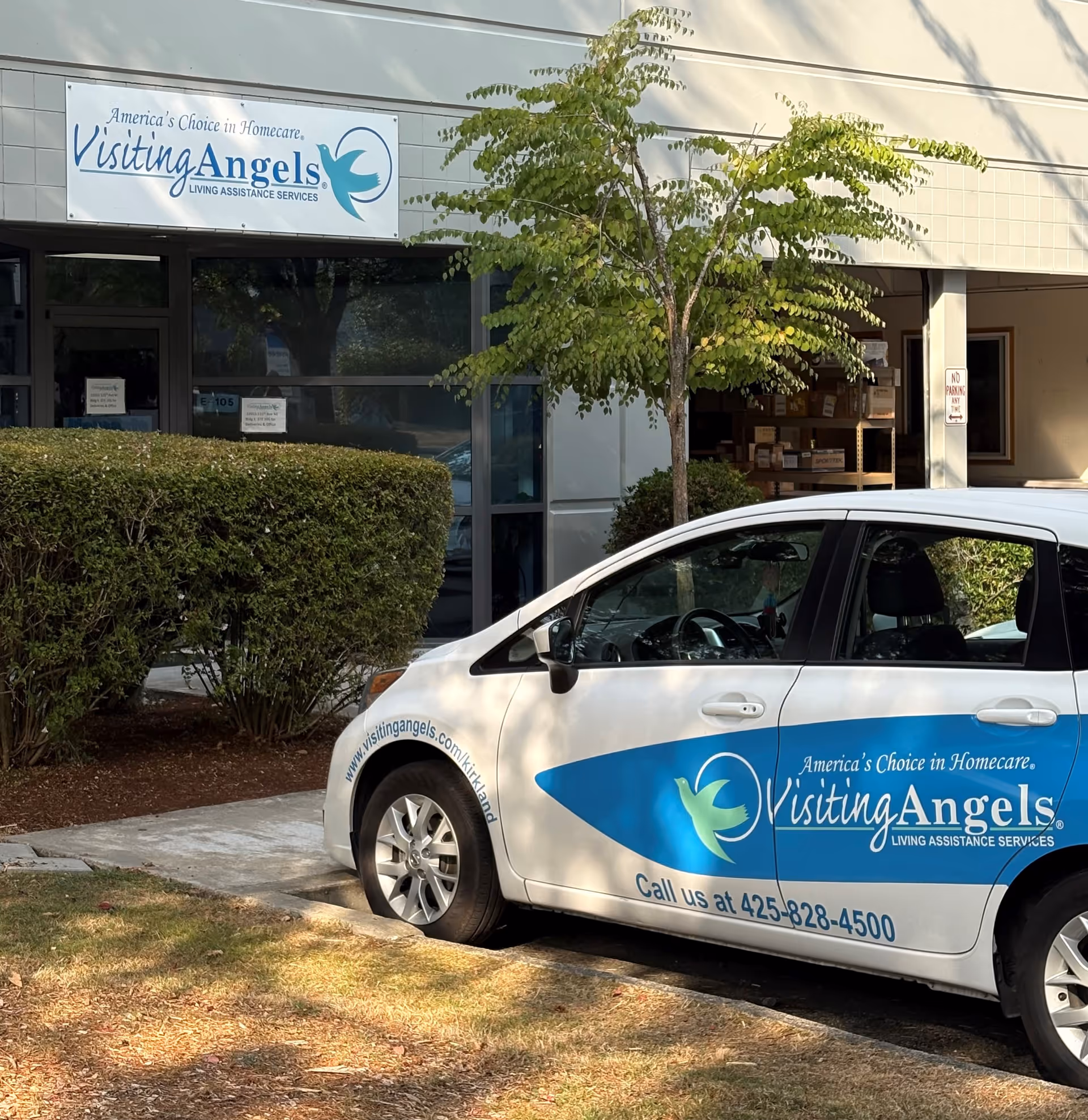 Visiting Angels storefront with branded van parked in front and greenery.