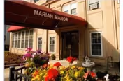 Front entrance of Marian Manor with a red awning and colorful flowers.