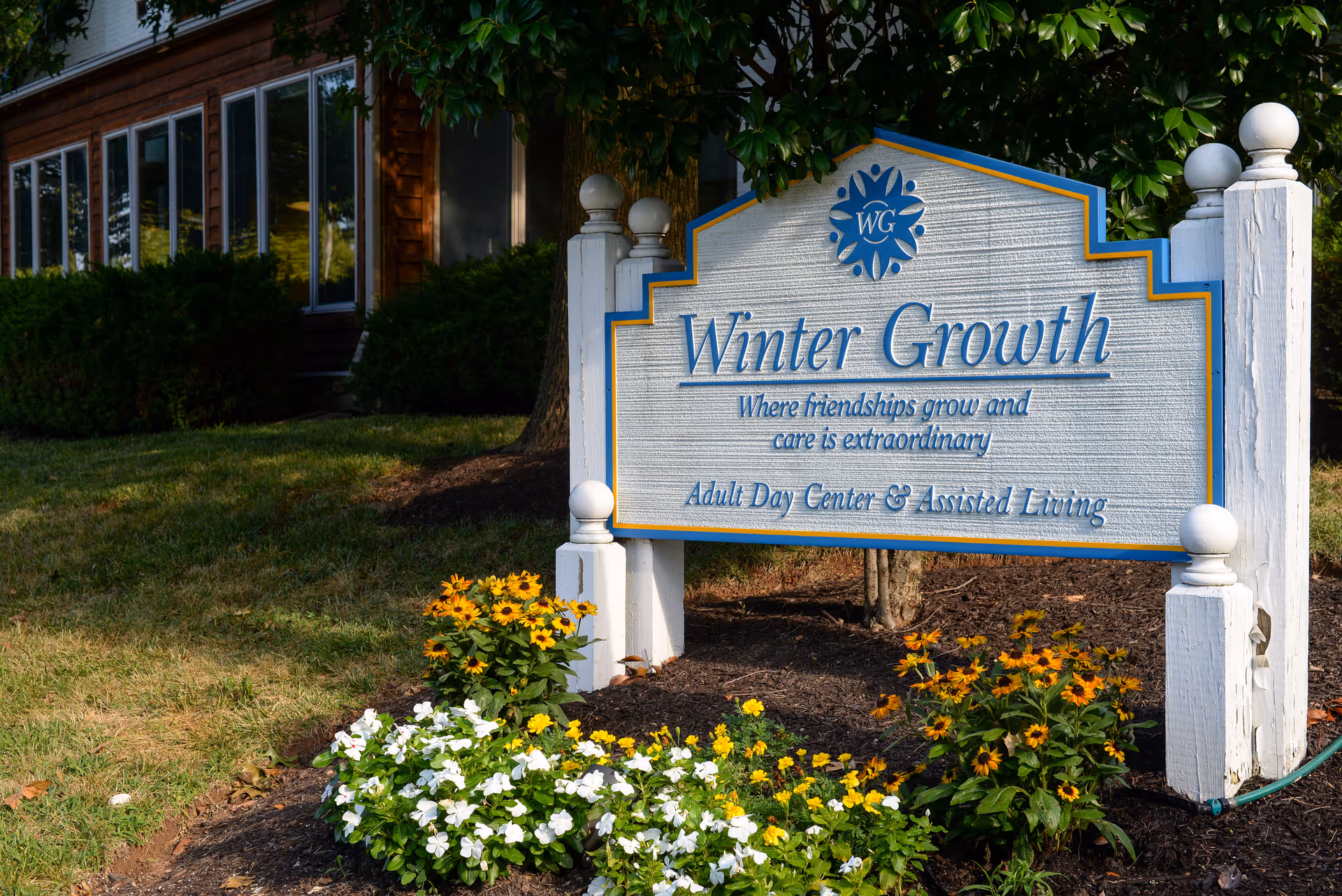 Winter Growth sign in front of a building with blooming flowers