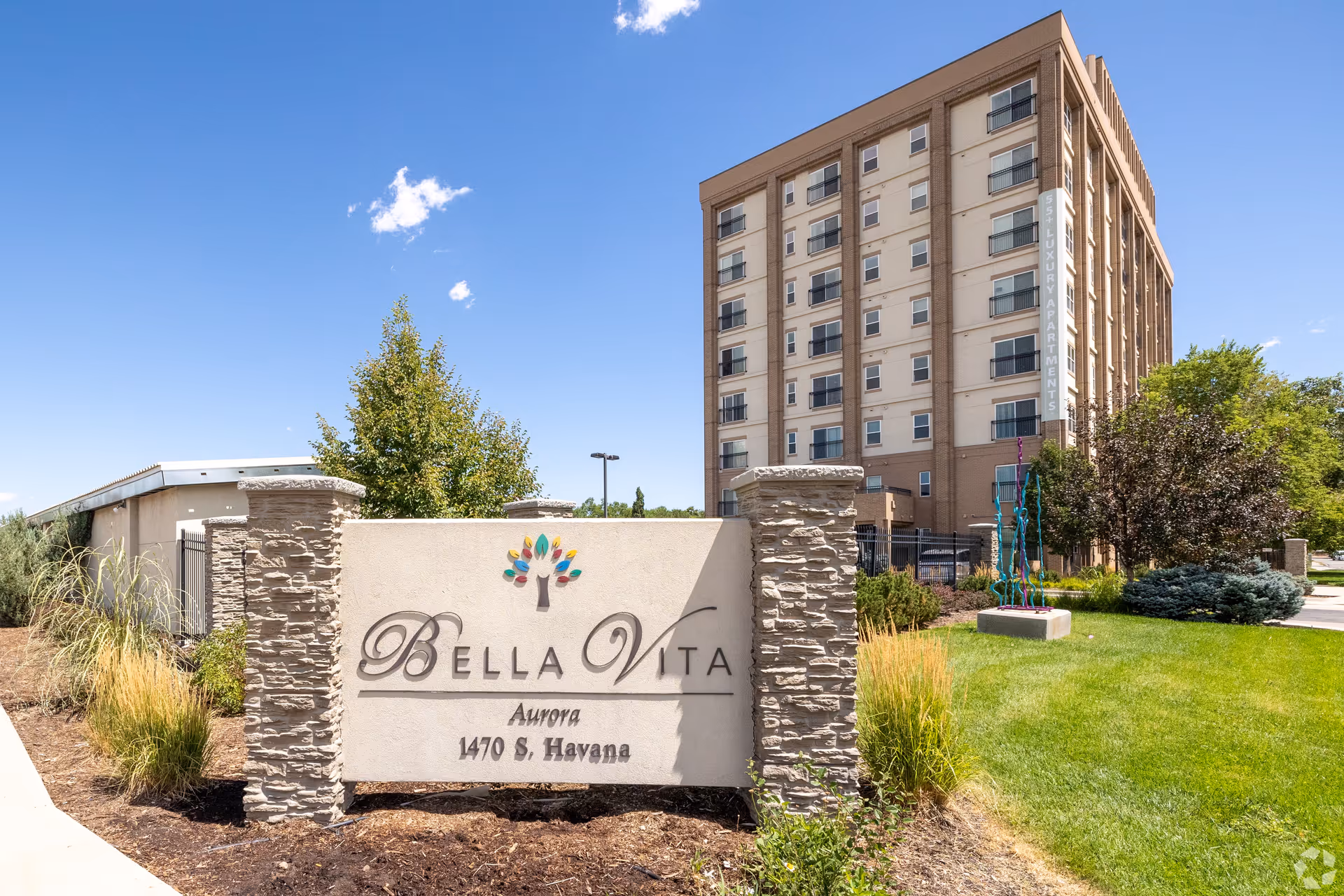 Exterior view of Bella Vita Senior Living with sign and tall building.