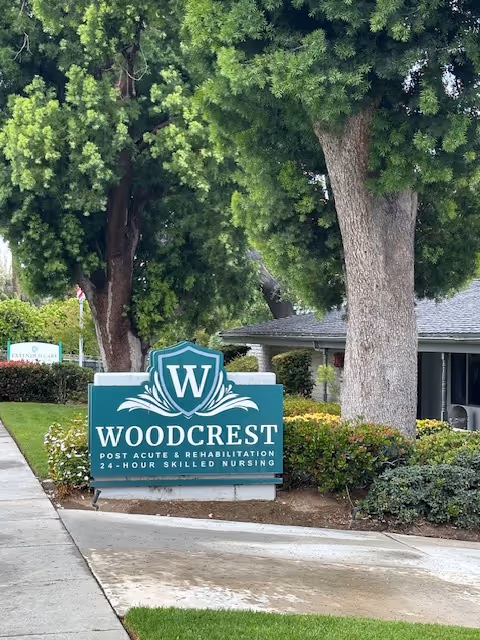 Woodcrest Post Acute Rehabilitation sign in front of trees beside a building