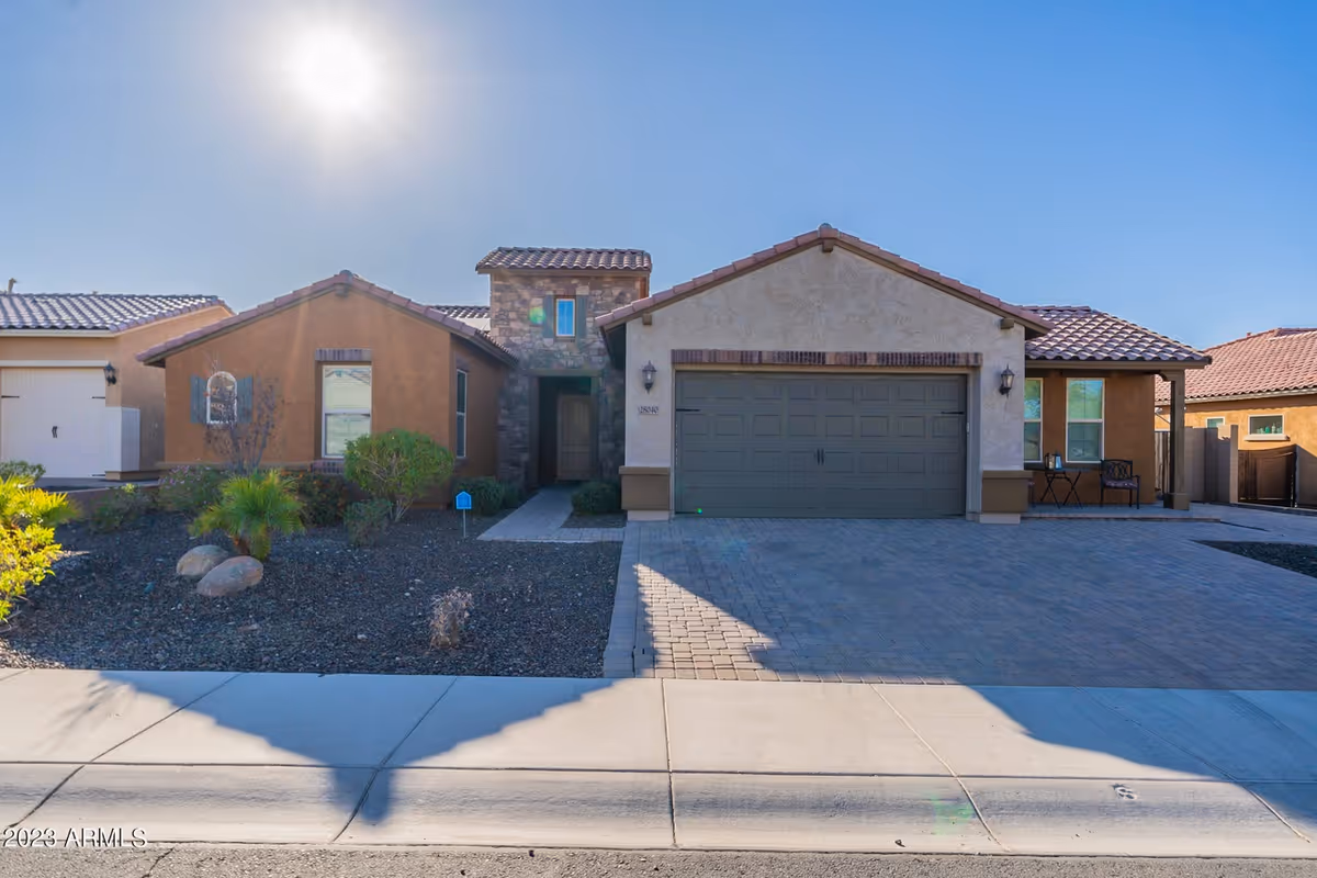 Front exterior of a single-story building with a two-car garage and desert landscaping.