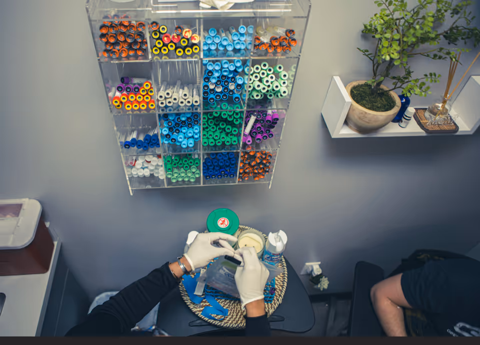 Gloved hands organize color-coded specimen tubes at a phlebotomy station.