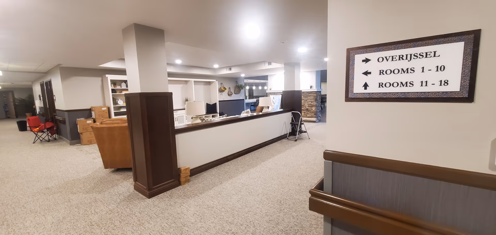 Indoor lobby at Overijssel facility with a reception desk and directional sign.