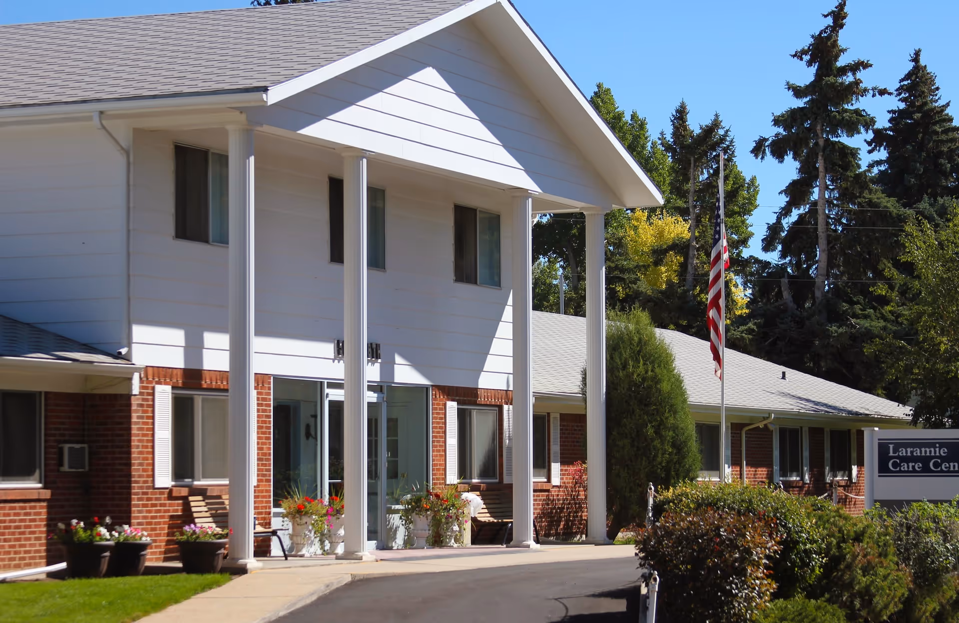 White-brick senior care center exterior with pillars, entrance, and a sign reading Laramie Care Center.