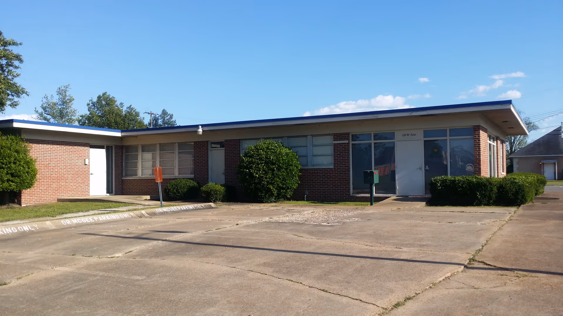 Single-story brick building with blue trim, glass entrance, and a wide parking lot.
