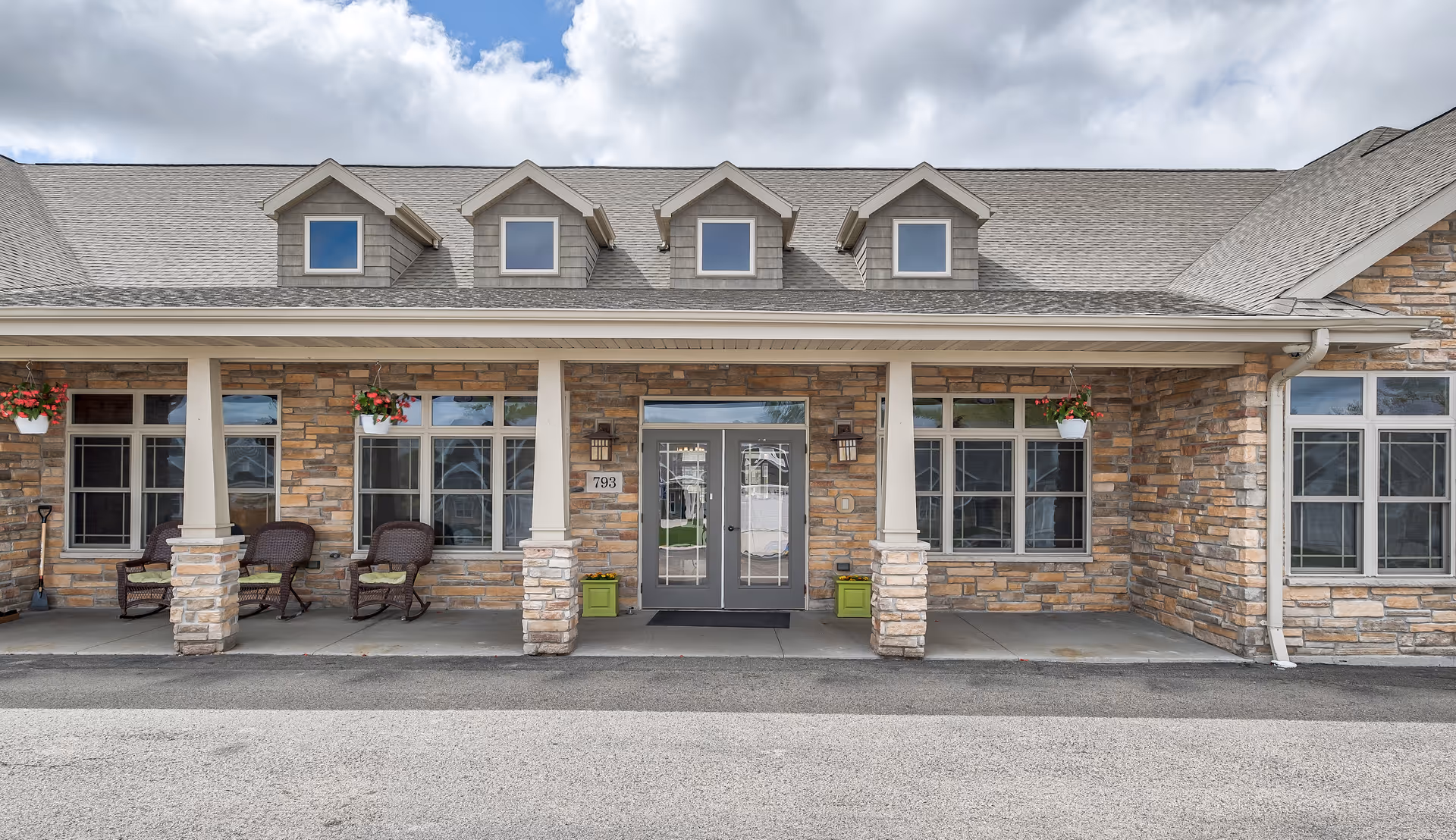 Stone exterior of a senior living facility with a covered front entrance and seating area.