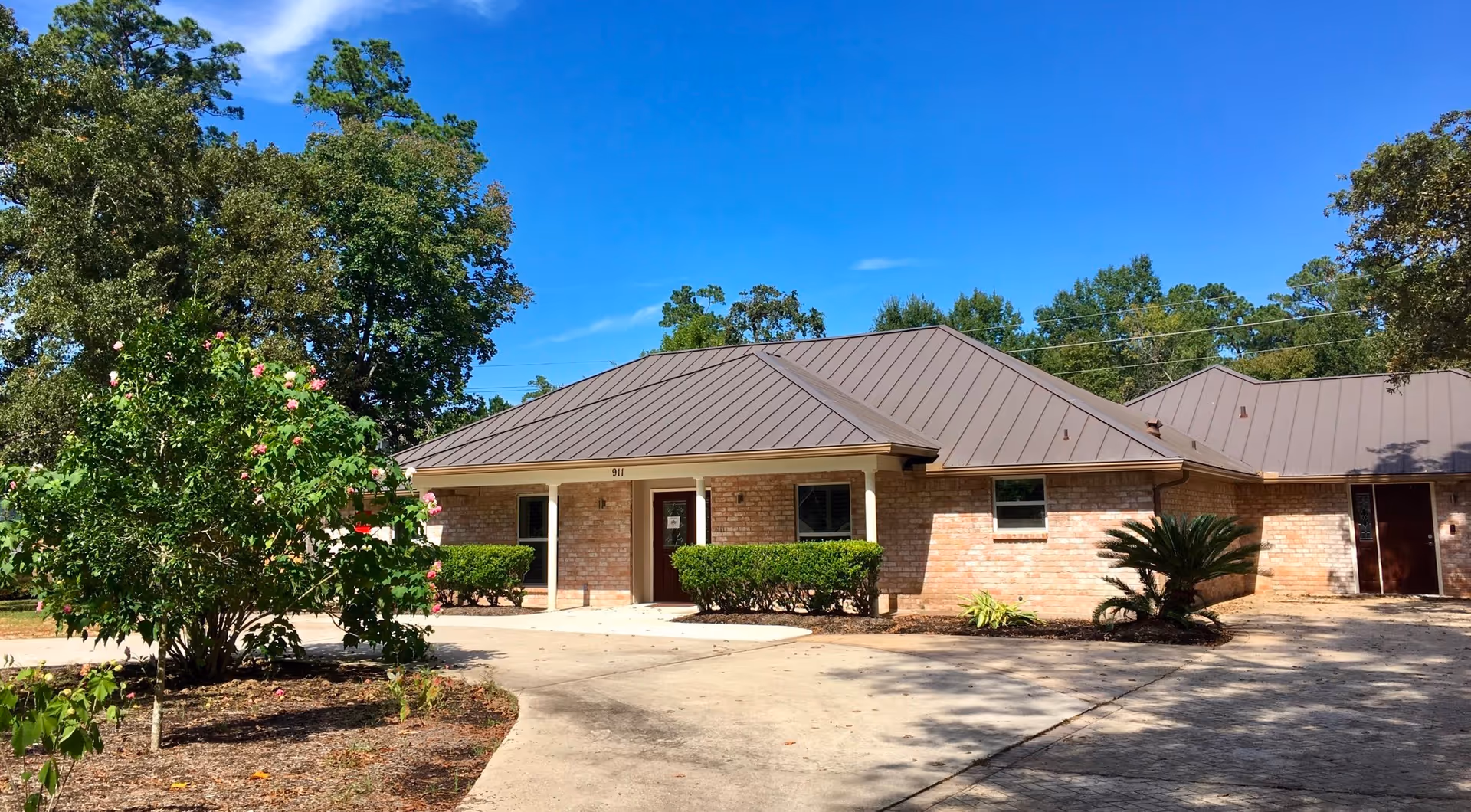 Single-story brick senior living facility with a metal roof and landscaped entrance.